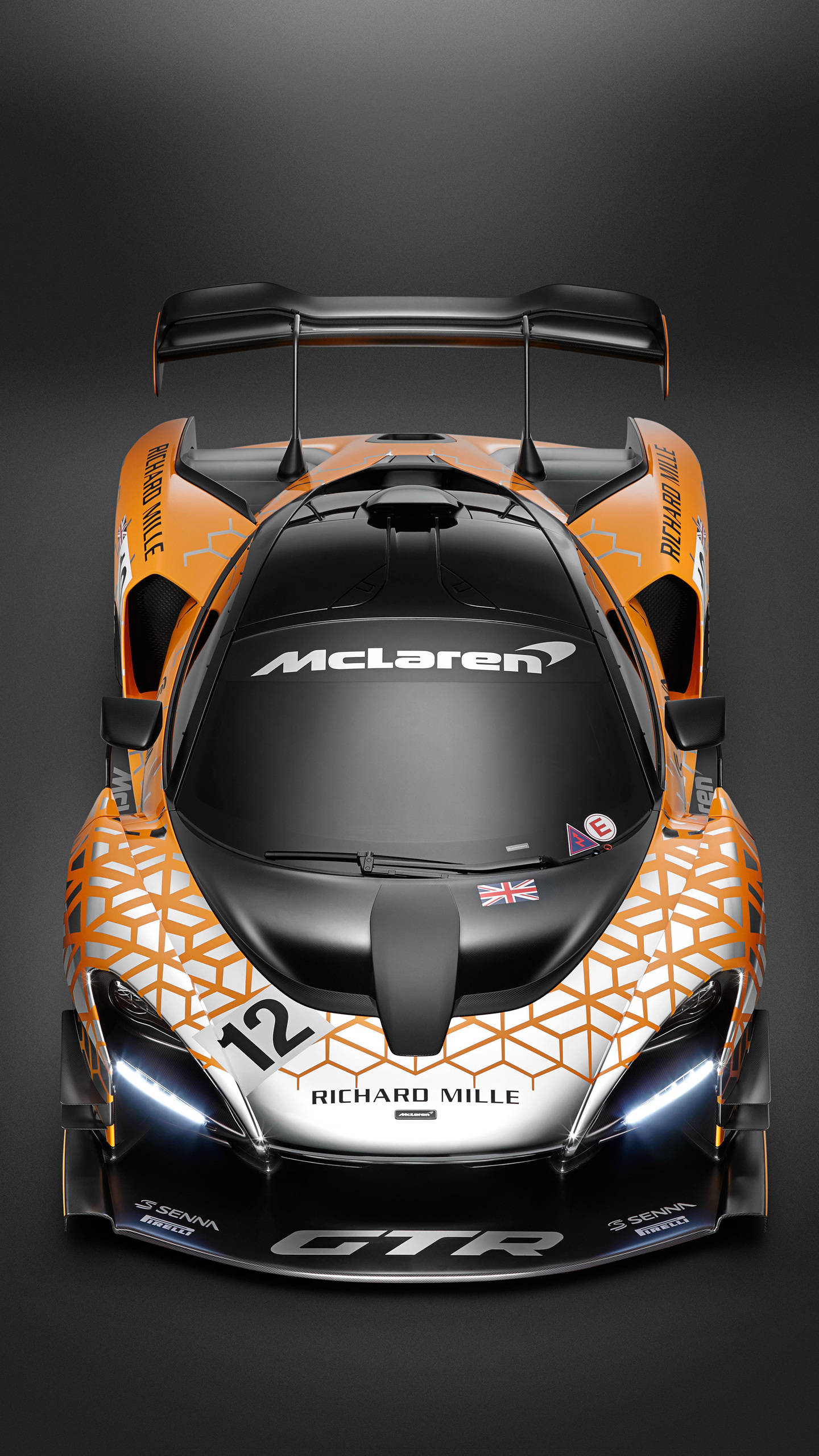 麥拉倫 桌布 壁紙 — 從上方俯瞰一輛時尚的橙色和黑色McLaren Senna GTR賽車，在黑暗的攝影棚背景下帶有發光的車頭燈。