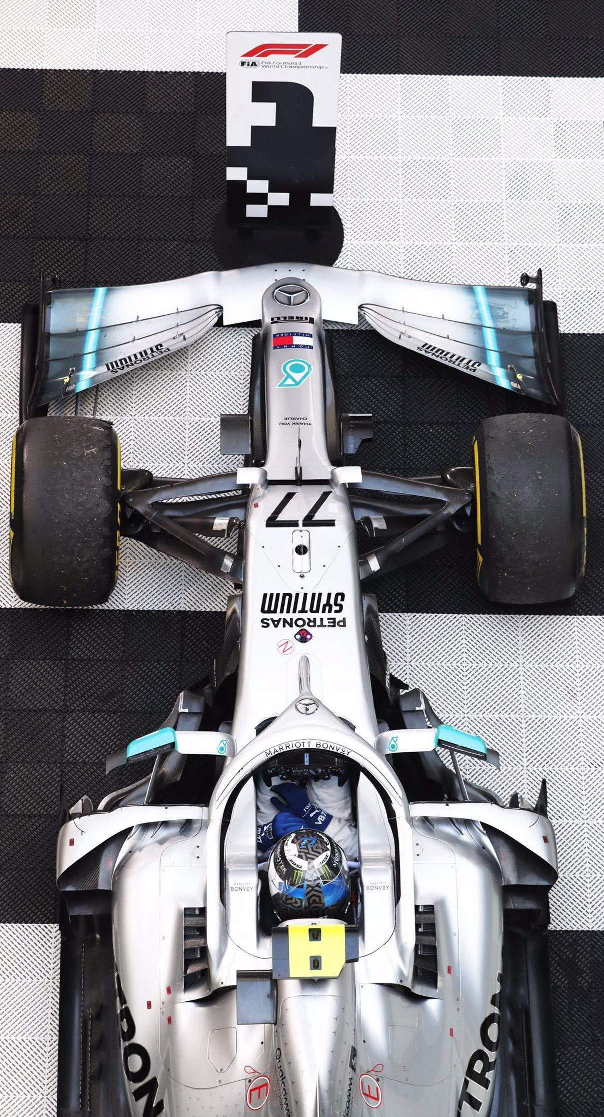 Valtteri Bottas 桌布 壁紙 — 從上方俯瞰一輛銀色一級方程式賽車，車號77，位於黑白格子網格上。