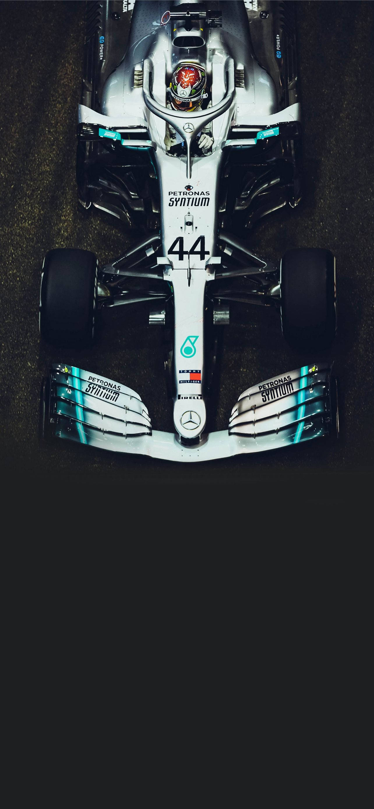桌布 壁紙 — 從上方俯瞰一輛銀色和藍綠色的 Formula 1 賽車，車號 44，在黑暗的賽道上。