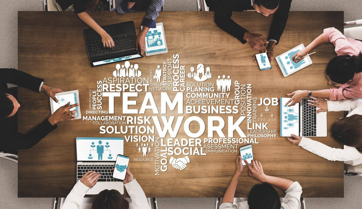 Work 桌布 壁紙 — 從上方俯瞰不同專業人士圍繞一張木桌協作，桌上擺放商業主題的文字藝術和數位設備。