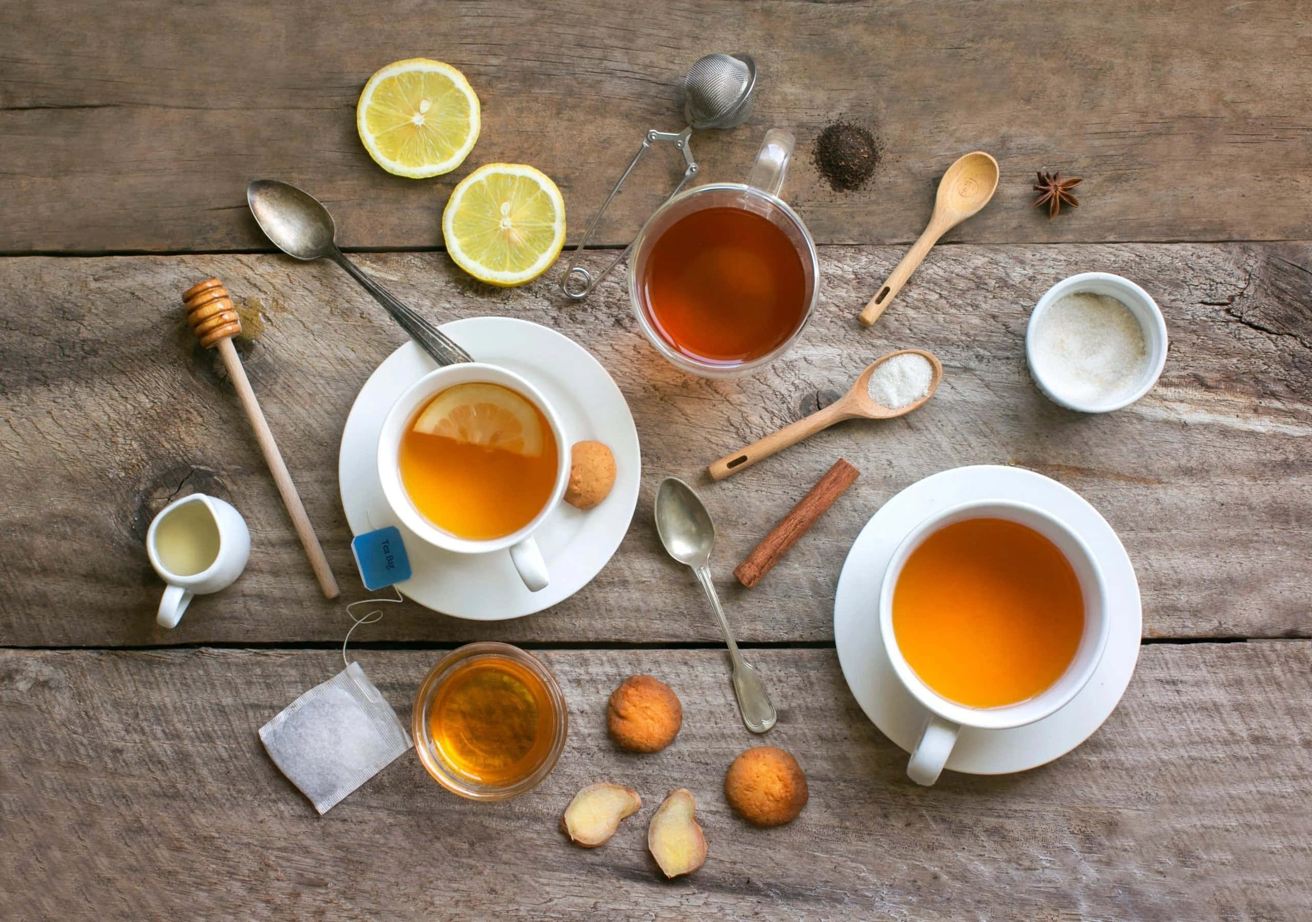 tea 桌布 壁紙 — 從上方俯瞰冒煙的茶杯和檸檬、蜂蜜、肉桂、餅乾等配料，擺放在鄉村風木桌上。