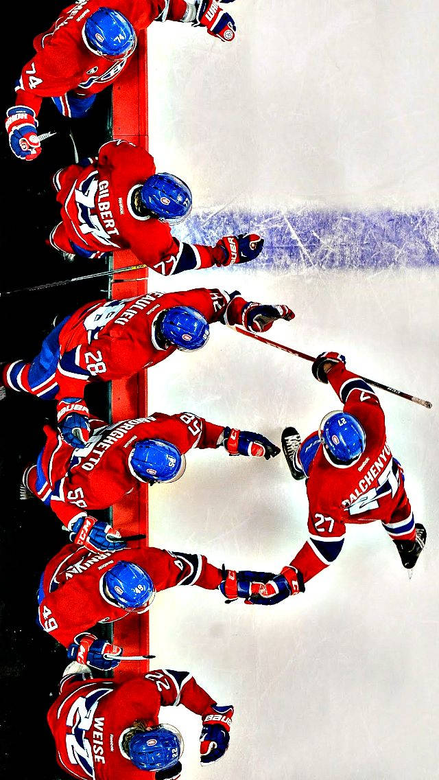 Washington Capitals 桌布 壁紙 — 從上方俯瞰冰球場上身穿紅色球衣的球員在板牆附近爭奪冰球的畫面。