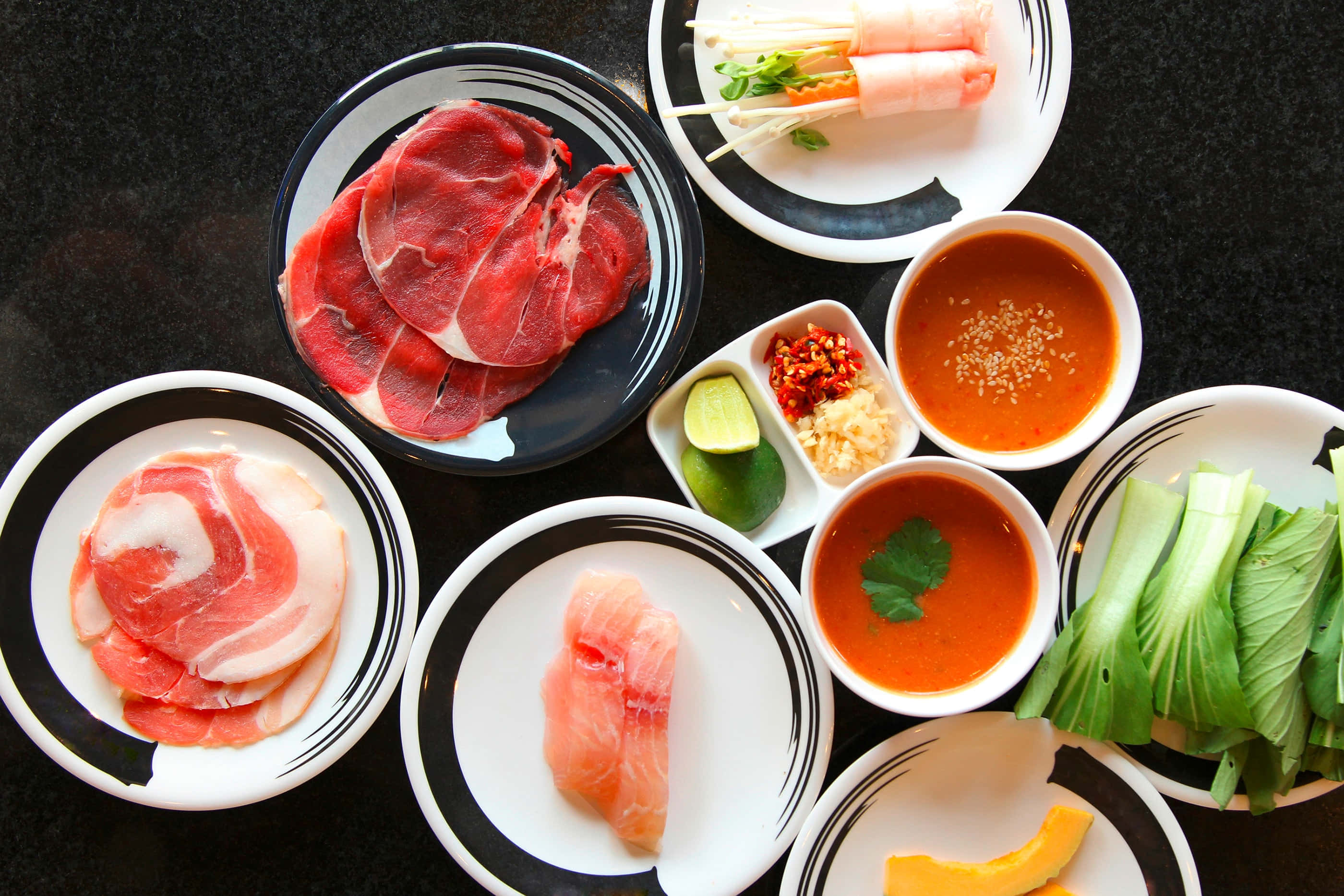 肉 桌布 壁紙 — 從上方俯瞰各種生肉、魚類和新鮮蔬菜整齊排列在黑白色盤子上，準備烹調。