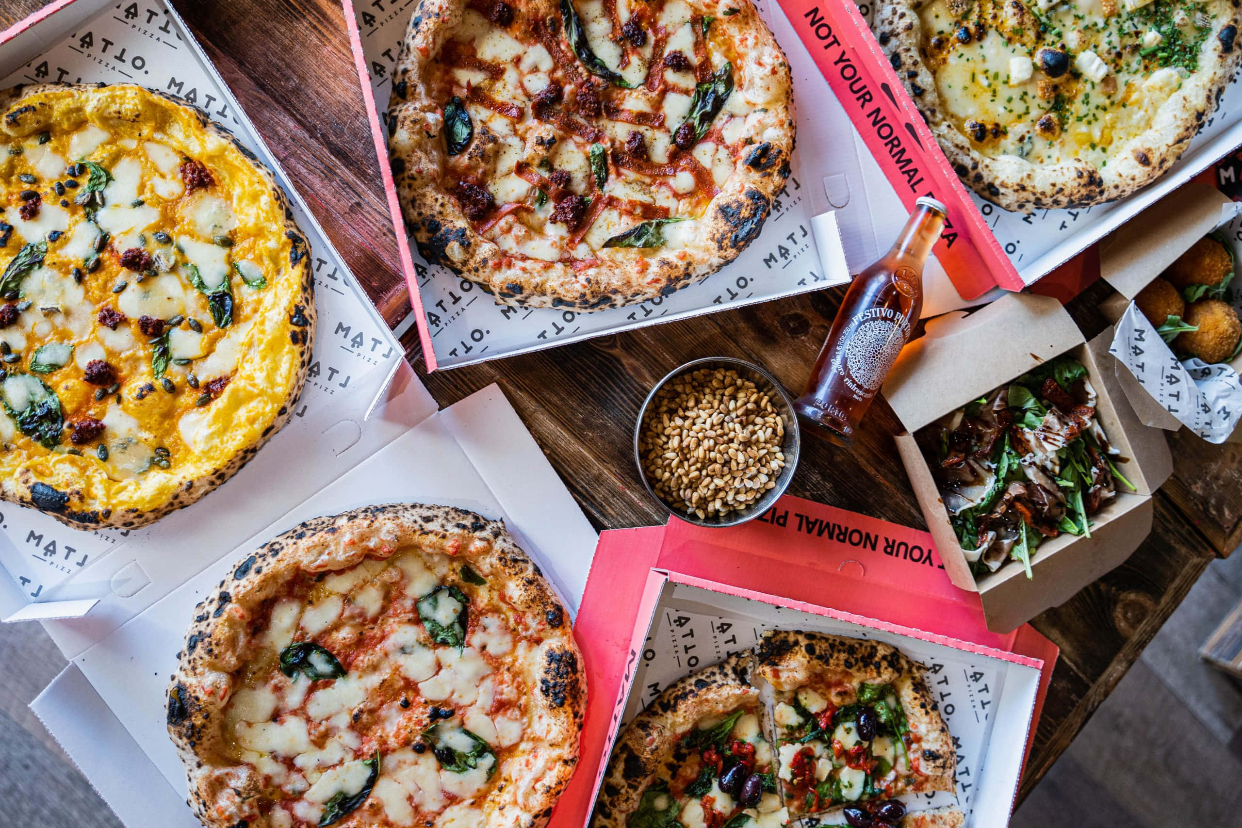 Pizza 桌布 壁紙 — 從上方俯瞰各種美食披薩和配菜擺放在質樸木桌上的景象。