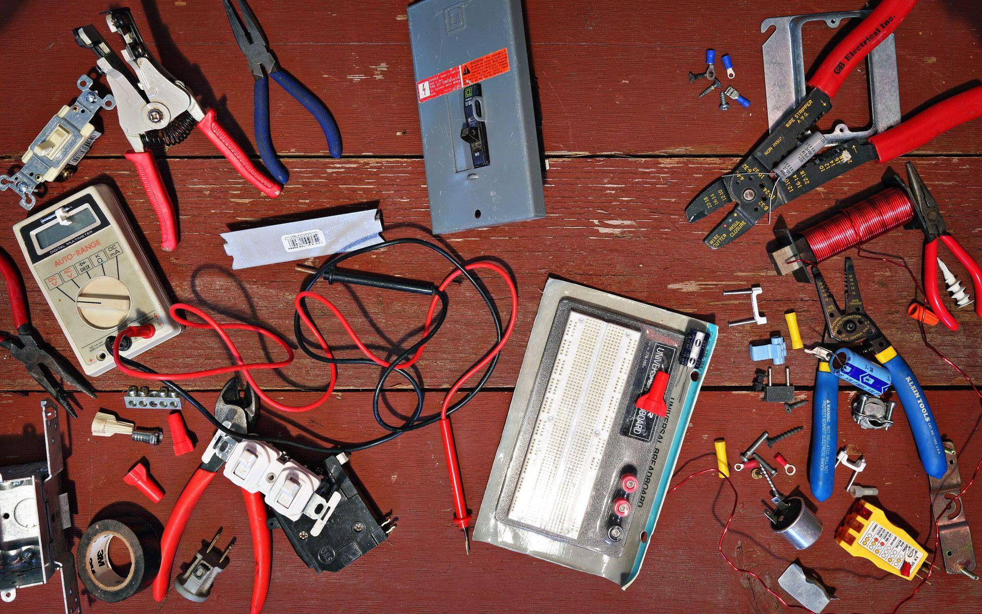 工具 桌布 壁紙 — 從上方俯瞰各種電動工具和零件散落在風化的紅色木製工作台上。
