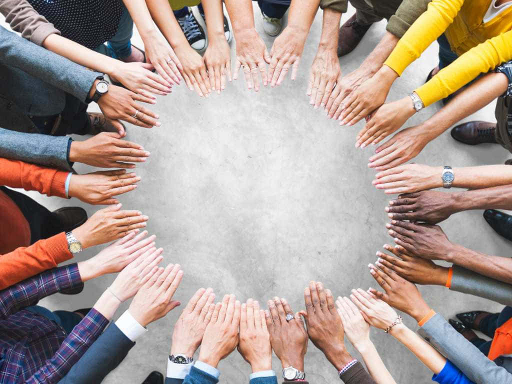 高清 桌布 壁紙 — 從上方俯瞰多種手在混凝土地板上形成一個圓圈，象徵團結與協作。