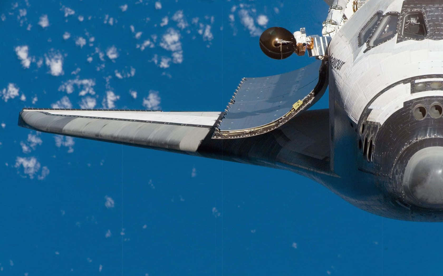 space shuttle 桌布 壁紙 — 從上方俯瞰太空梭的機翼和機頭部分，背景是充滿活力的藍色地球和散落的白色雲層。