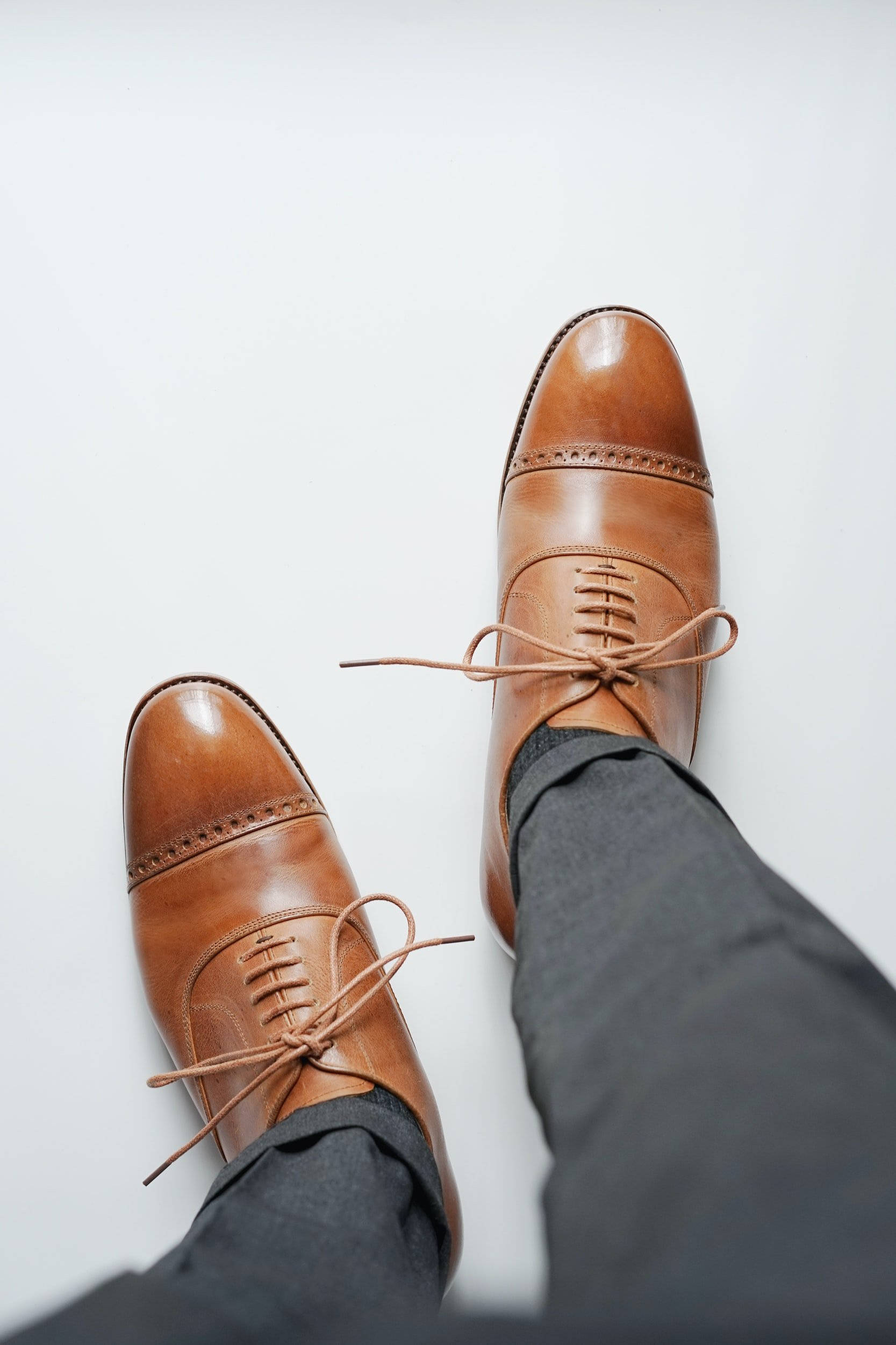 Clothes 桌布 壁紙 — 從上方俯瞰拋光棕色皮革 cap-toe 正裝鞋，鞋帶未繫，置於純白背景上。