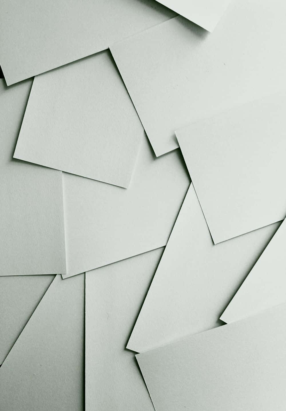 White Paper 桌布 壁紙 — 從上方俯瞰散落的淺灰色紙張，營造出極簡紋理構圖。