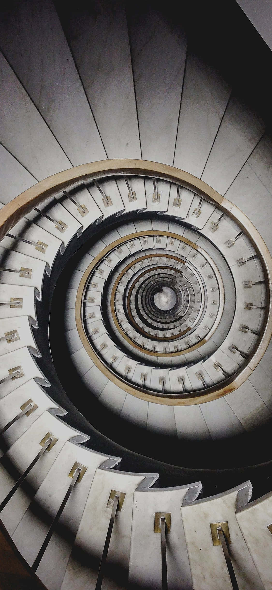 stairs 桌布 壁紙 — 從上方俯瞰的戲劇性畫面，一道螺旋混凝土樓梯向下延伸至陰暗深處。