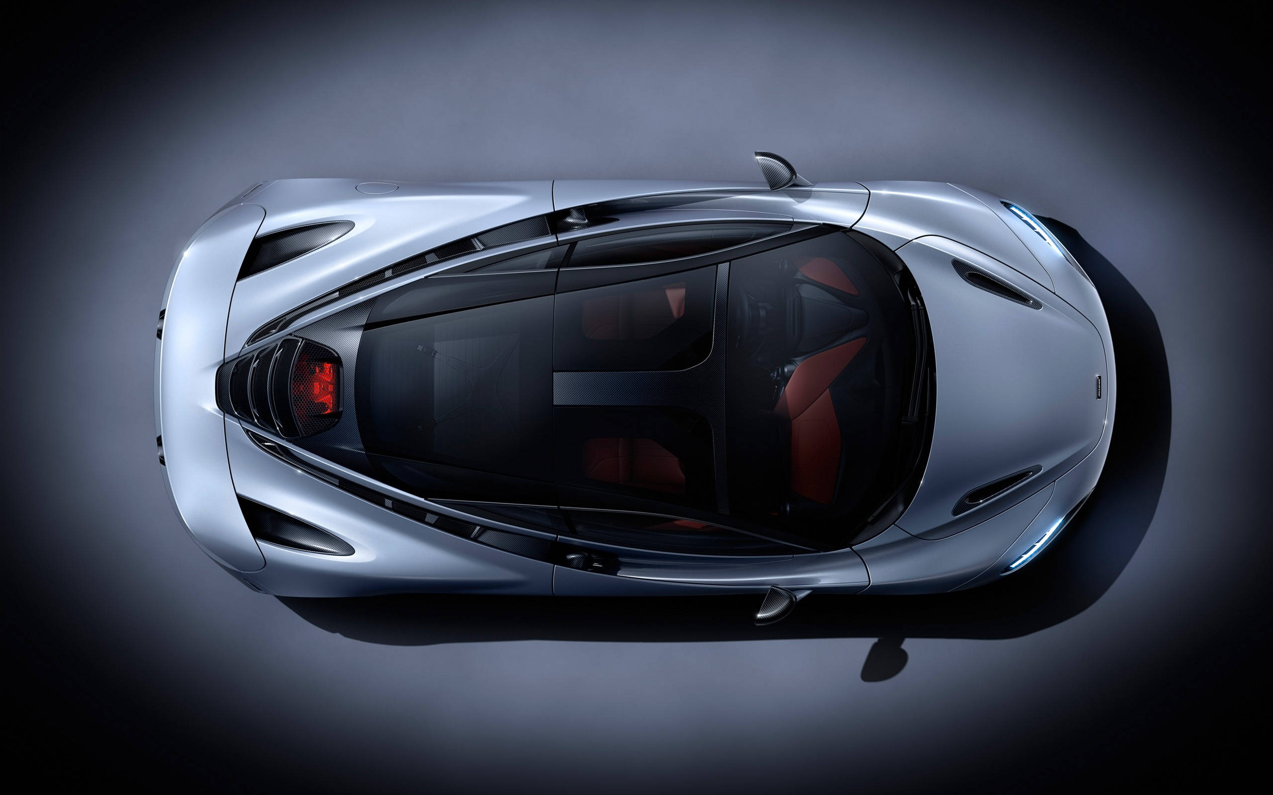 mclaren 720s 4K 桌布 壁紙 — 從上方俯瞰的時尚銀色跑車，配備紅色內飾座椅和發光尾燈，背景為深色工作室。