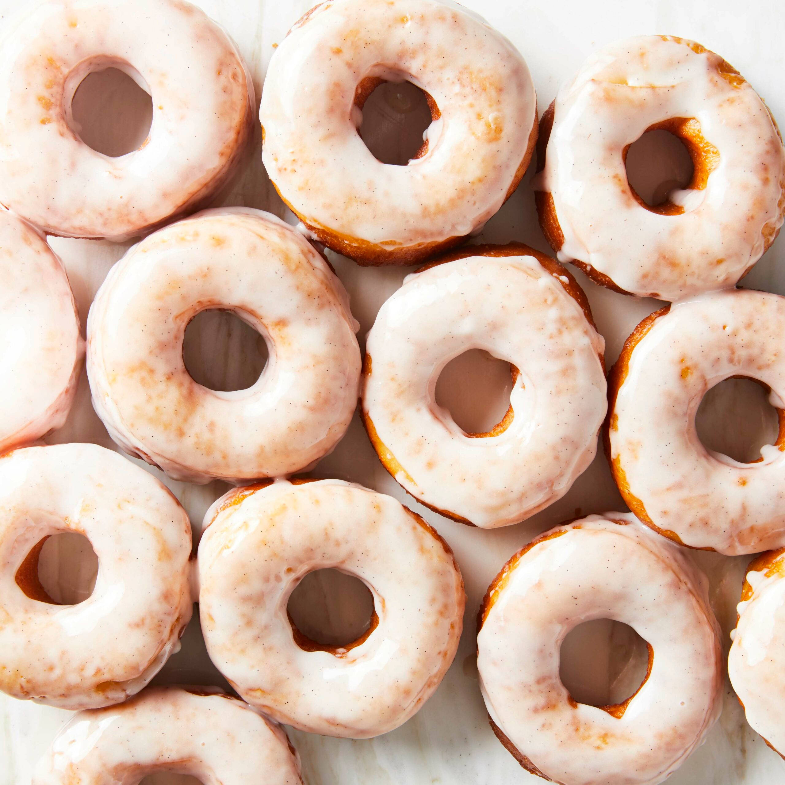 Donut 桌布 壁紙 — 從上方俯瞰的視角，展示在淺色表面上排列的糖霜肉桂甜甜圈。