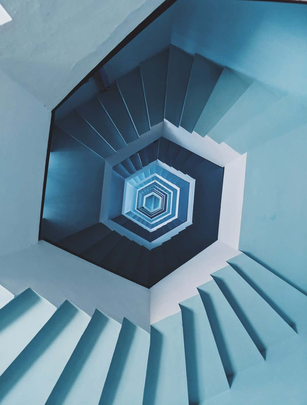 Hexagon 桌布 壁紙 — 從上方俯瞰的迷人幾何螺旋樓梯，帶有冷藍色調和銳利陰影，形成催眠般的六邊形圖案。
