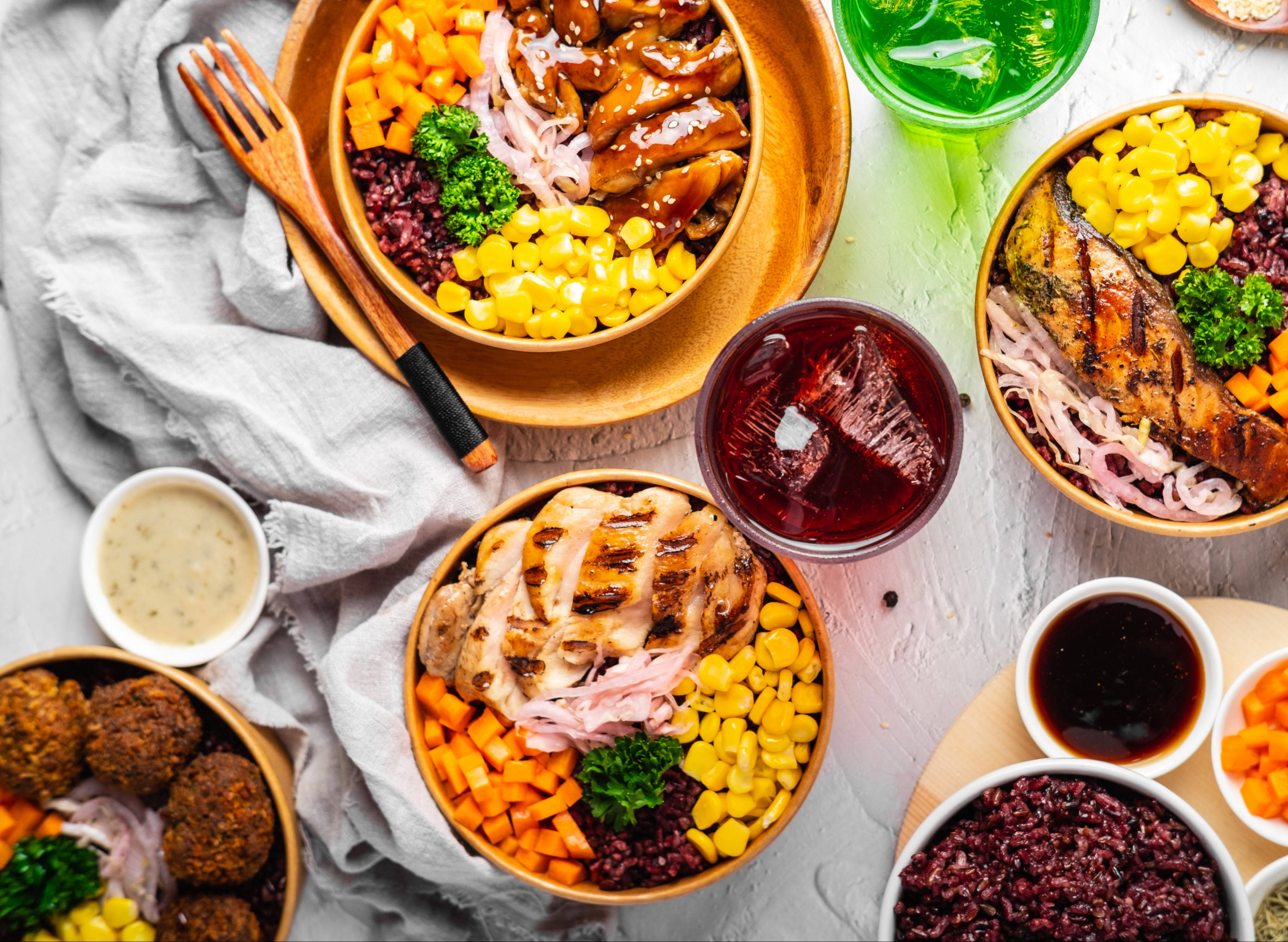 Healthy Food 桌布 壁紙 — 從上方俯瞰色彩繽紛的碗，裝滿烤雞、玉米、紅蘿蔔和紅米，擺放在淺色木質表面上。