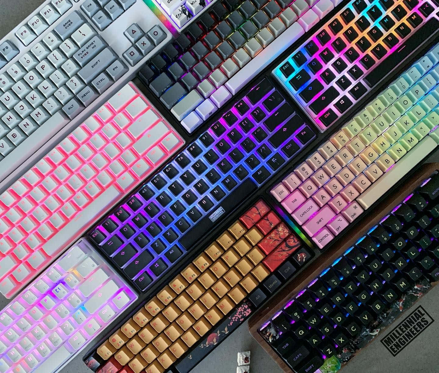 Cute Keyboard 桌布 壁紙 — 從上方拍攝的多個機械鍵盤的鮮豔照片，帶有發光的彩虹背光和各種鍵帽設計。