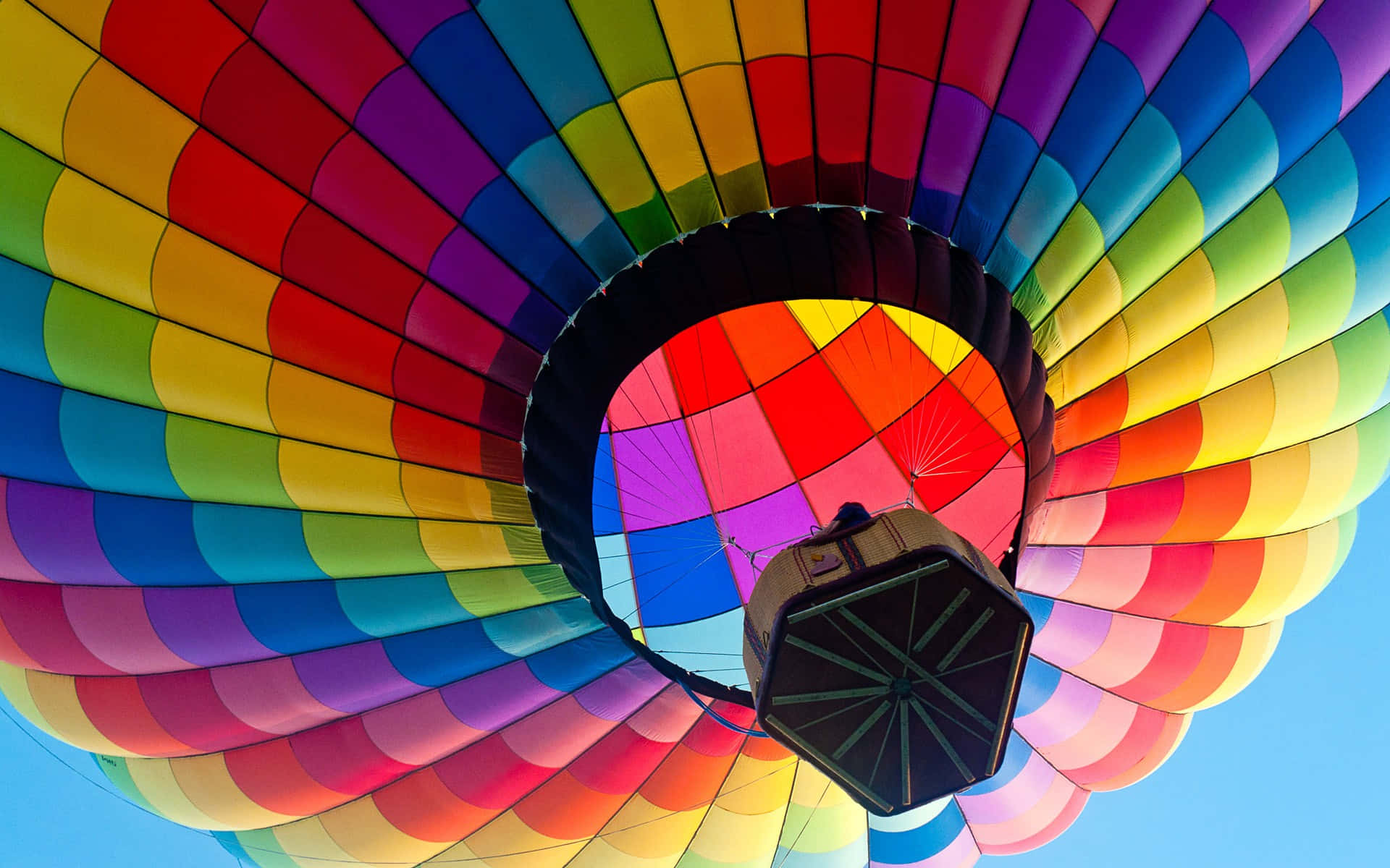 Hot Air Balloon 桌布 壁紙 — 從下方仰望色彩繽紛的彩虹色熱氣球篷頂，映襯著清澈的藍天。