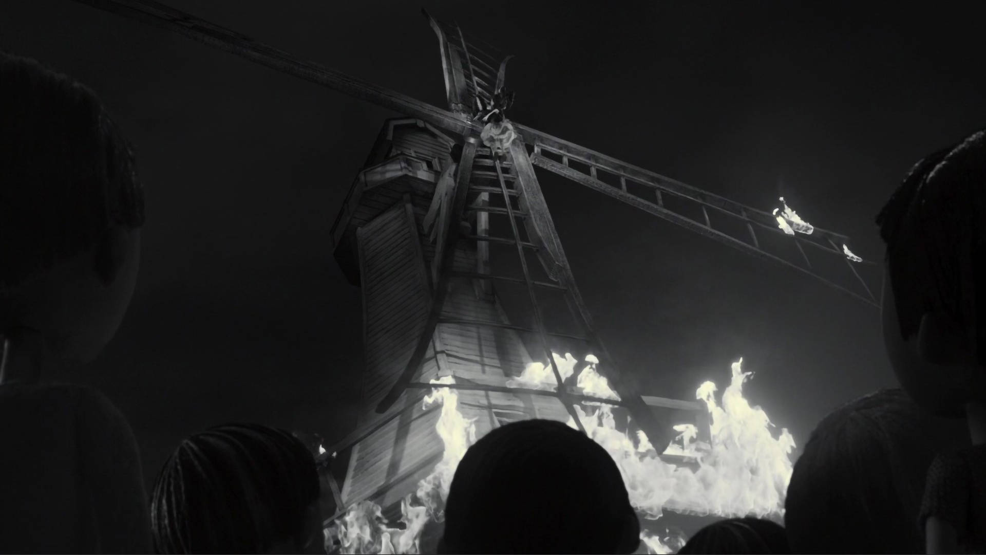 Frankenweenie 桌布 壁紙 — 從下方觀看，一座燃燒的風車在夜晚，由剪影般的旁觀者觀看，呈現強烈的黑白場景。
