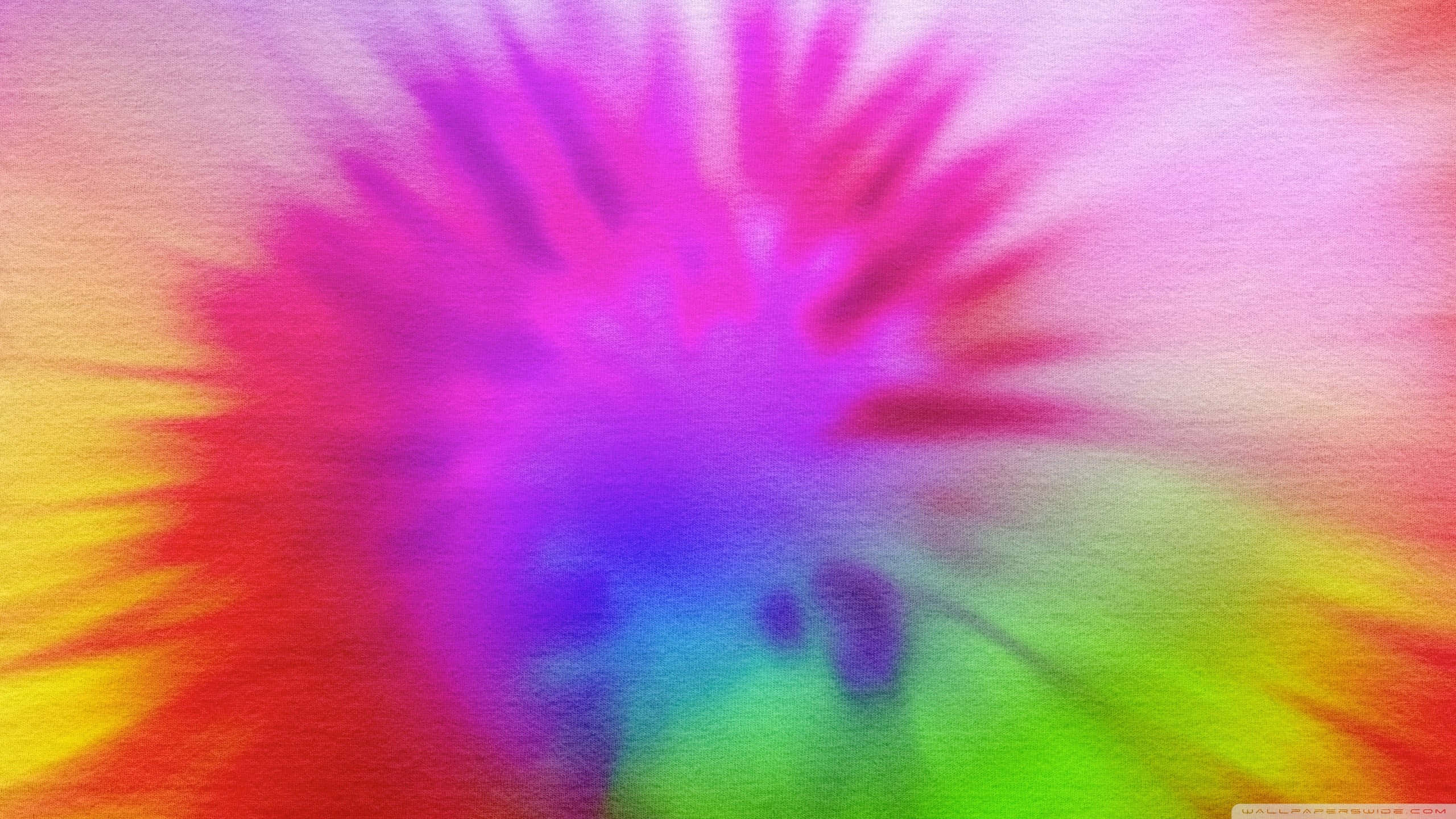 High Resolution Tie Dye 桌布 壁紙 — 從中央紫色核心向外輻射的鮮豔抽象彩虹色爆炸。