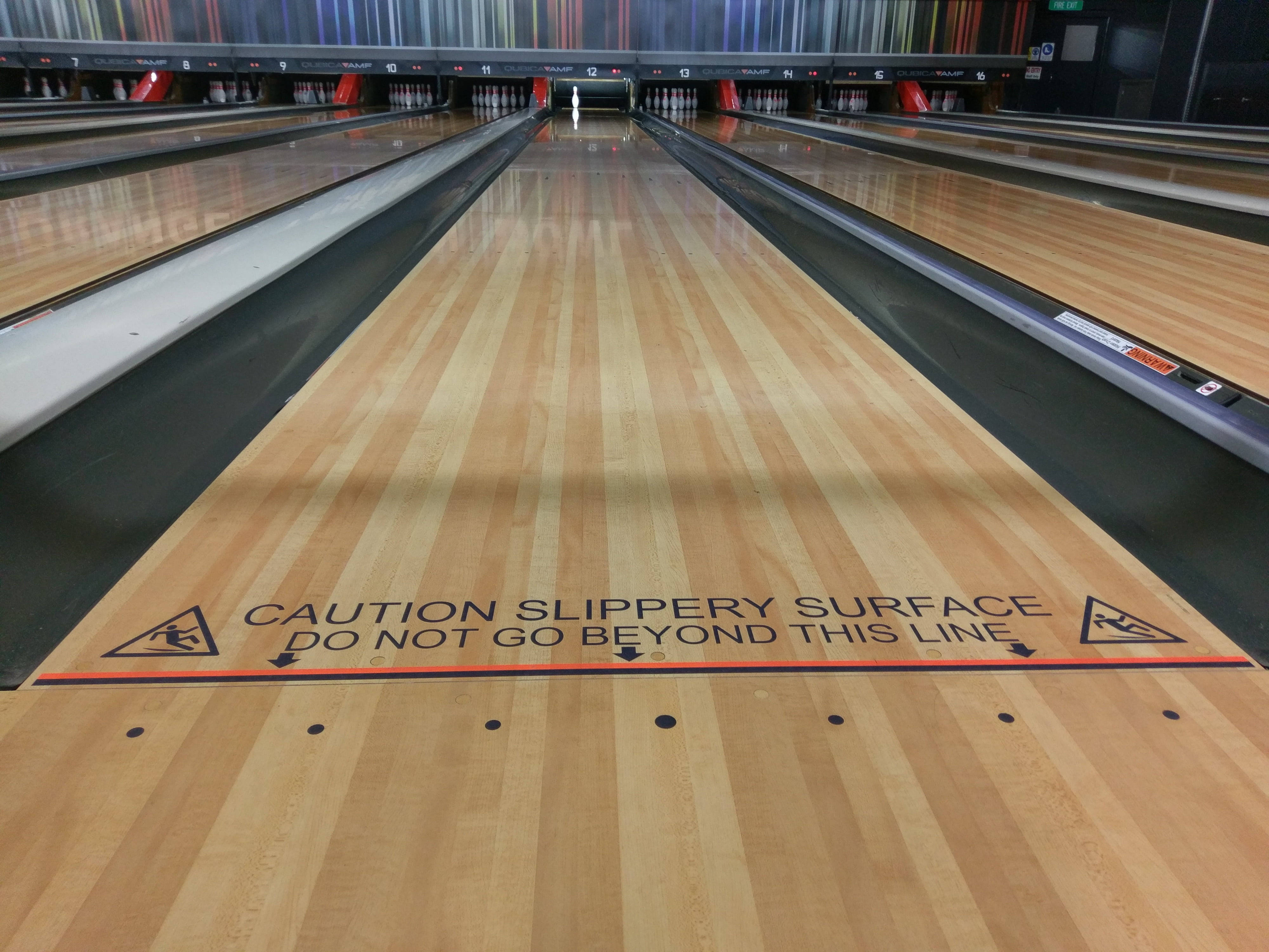 Bowling 桌布 壁紙 — 從低角度俯瞰拋光木製保齡球道，犯規線上有警告標誌。