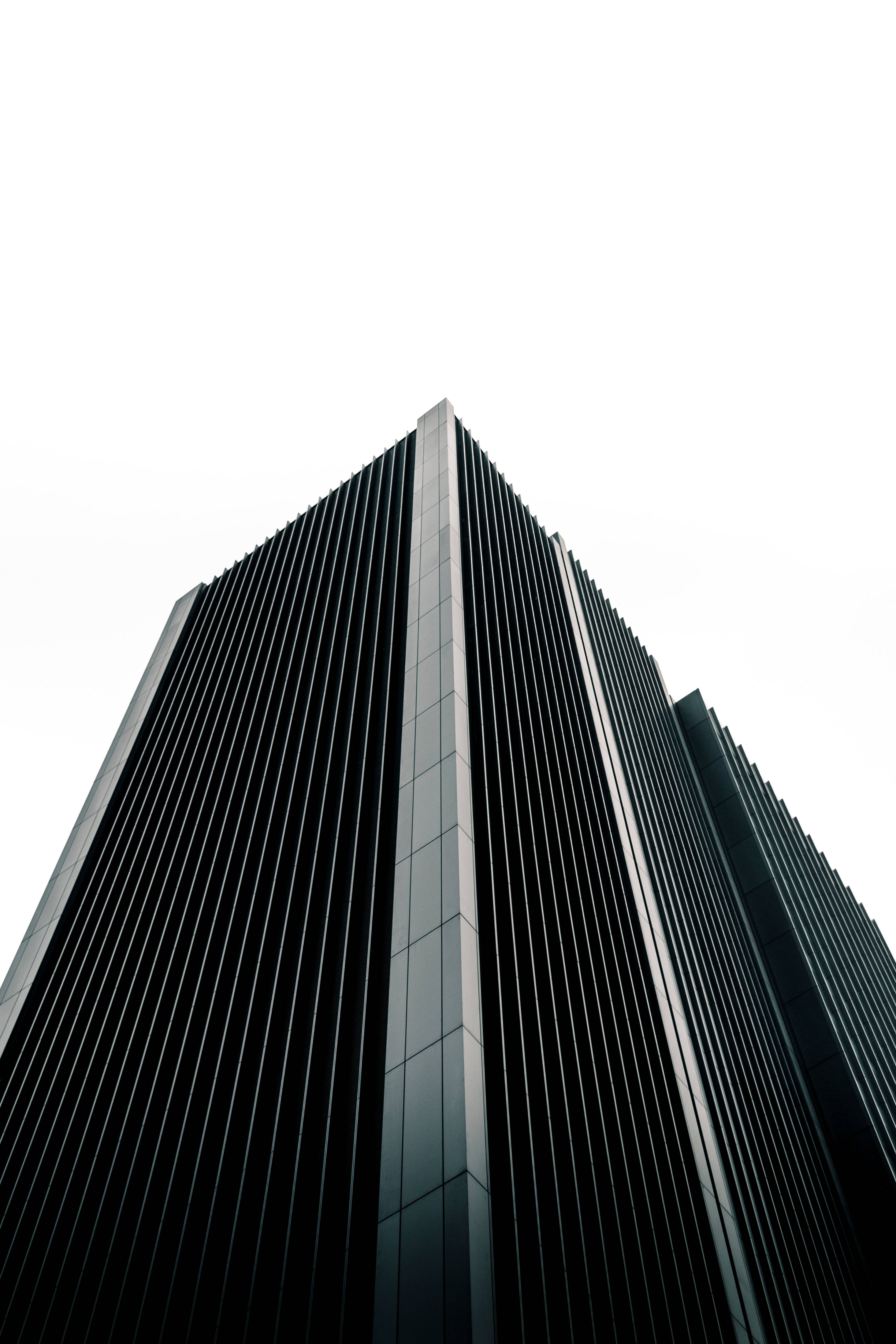Futuristic City 桌布 壁紙 — 從低角度拍攝的時尚現代摩天大樓，垂直玻璃面板伸向明亮的白色天空。