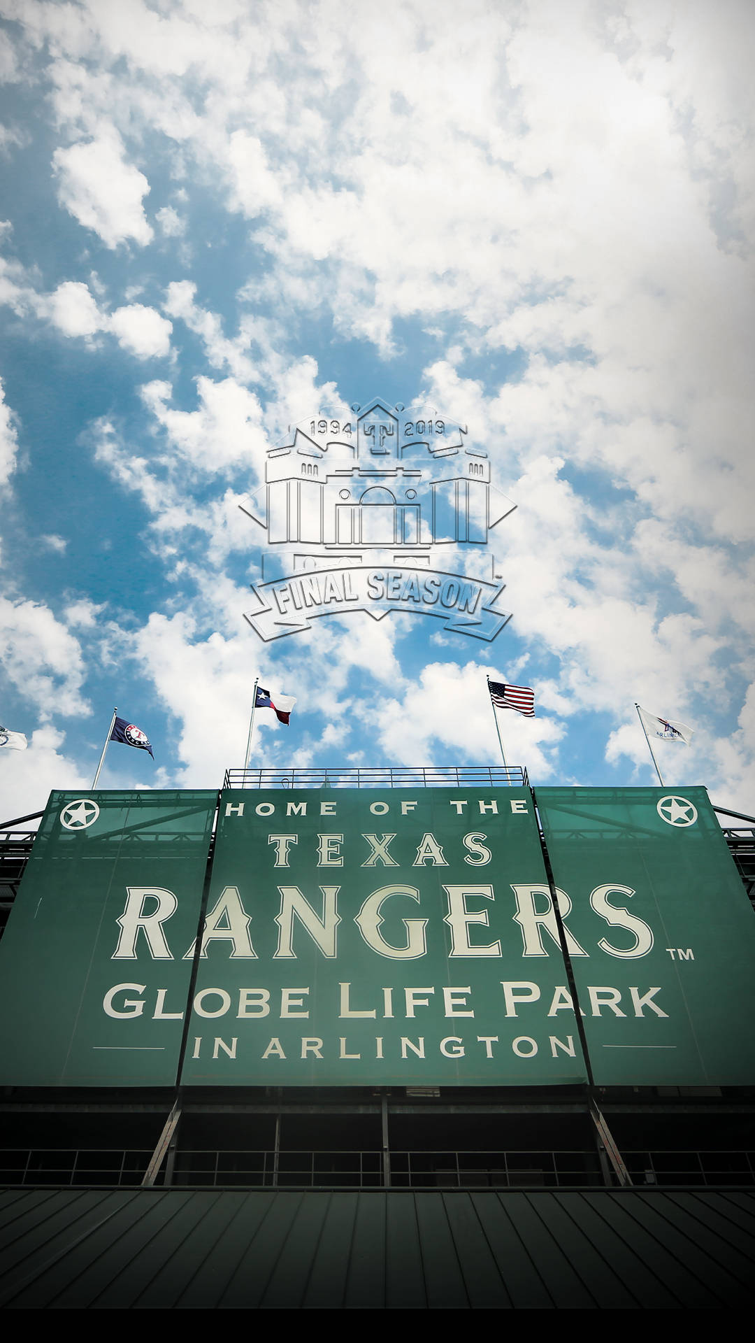 Texas Rangers 桌布 壁紙 — 從低角度觀看Globe Life Park的綠色標誌，背景是明亮的藍天、蓬鬆的白雲和飄揚的旗幟。