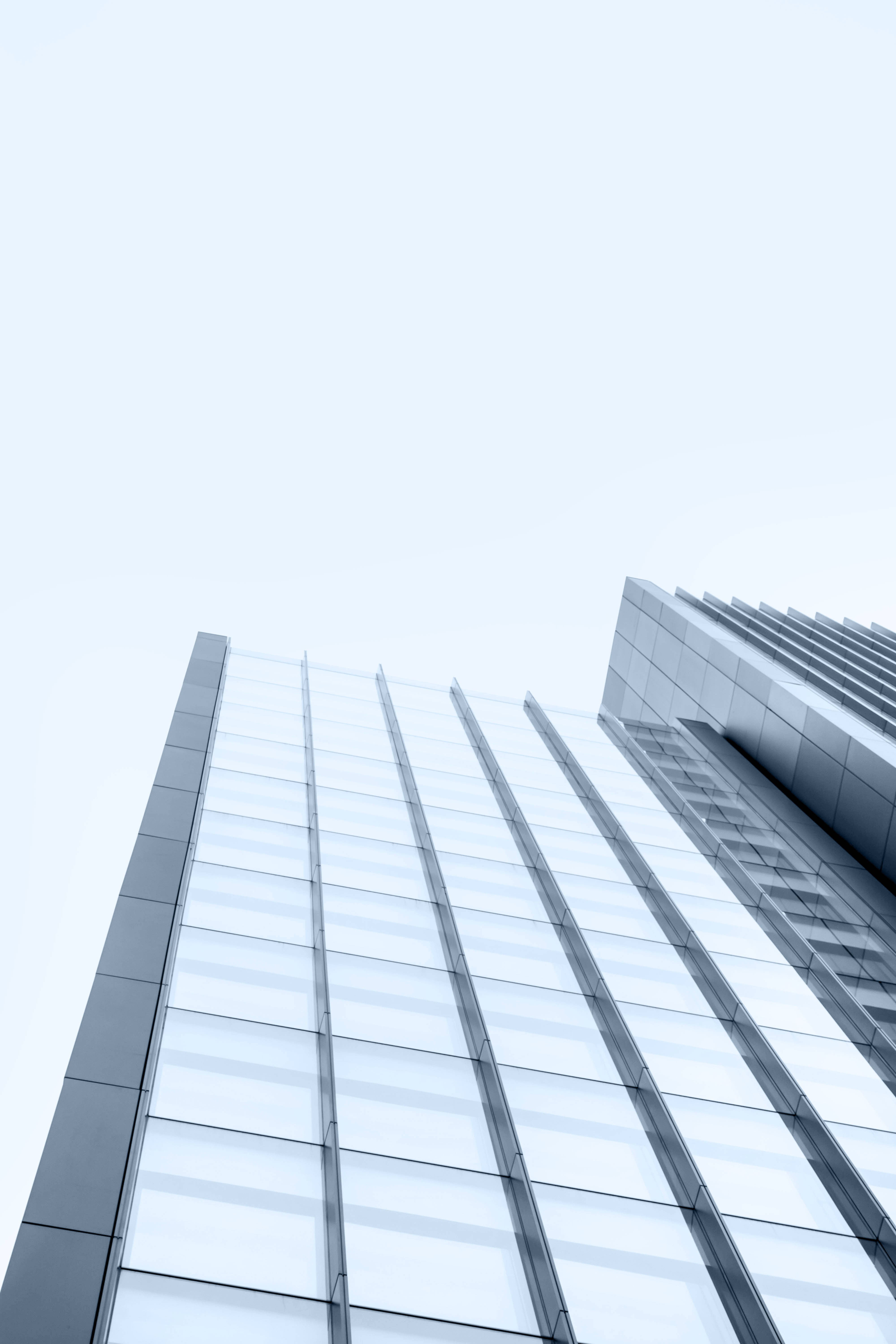Skyscraper 桌布 壁紙 — 從低角度觀看一座時尚的玻璃摩天大樓，以幾何精準度伸入蒼白的天空。