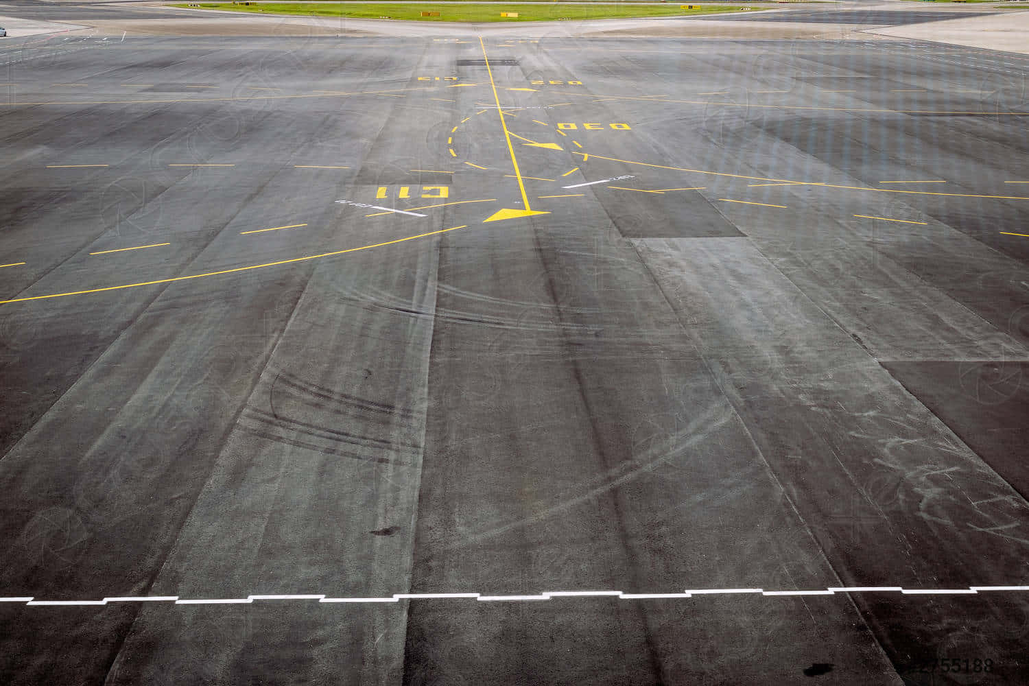 Runway 桌布 壁紙 — 從低角度觀看一條經風化的機場停機坪，上面有黃色跑道標記和深色瀝青上的輪胎滑痕。