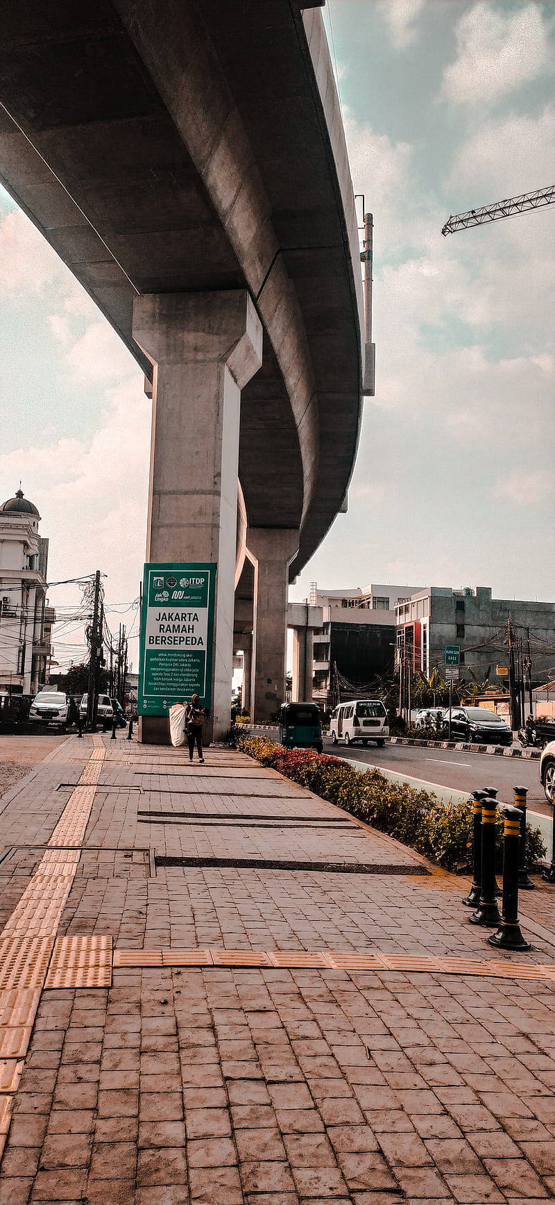 Jakarta 桌布 壁紙 — 從低角度觀看巨型混凝土天橋下的城市街道景觀，設有行人路和遠處的城市建築。
