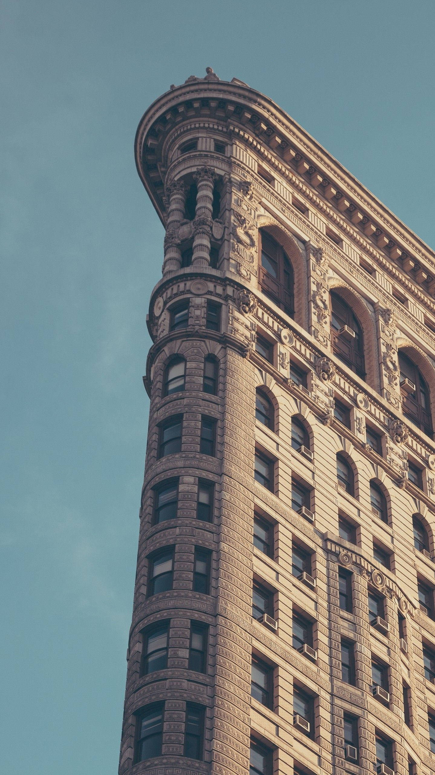 Flatiron Building 桌布 壁紙 — 從低角度觀看紐約市標誌性的熨斗大廈，背景是清澈的藍天。