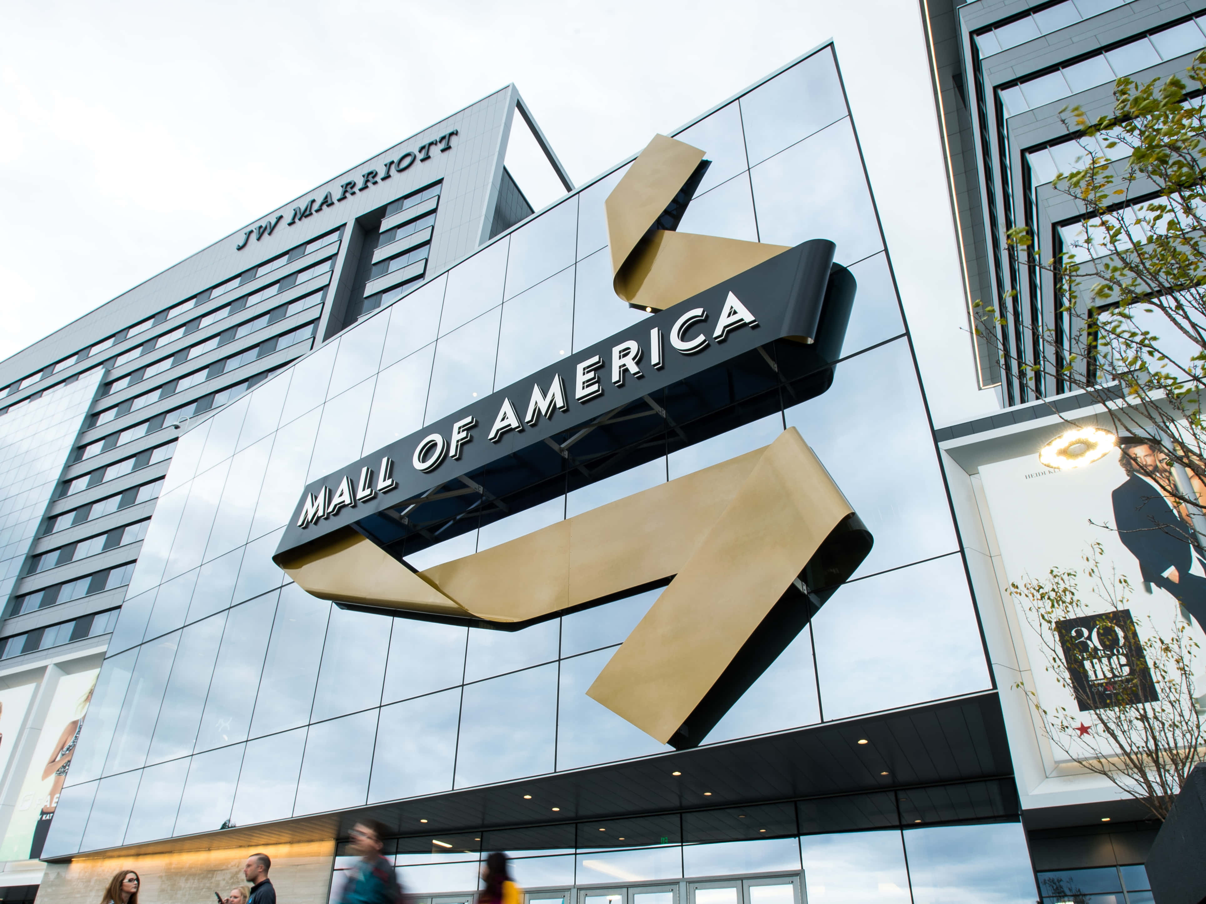 Mall Of America 桌布 壁紙 — 從低角度觀看美國購物中心標誌性的金色箭頭標誌，背景為玻璃幕牆，上方是JW萬豪酒店。