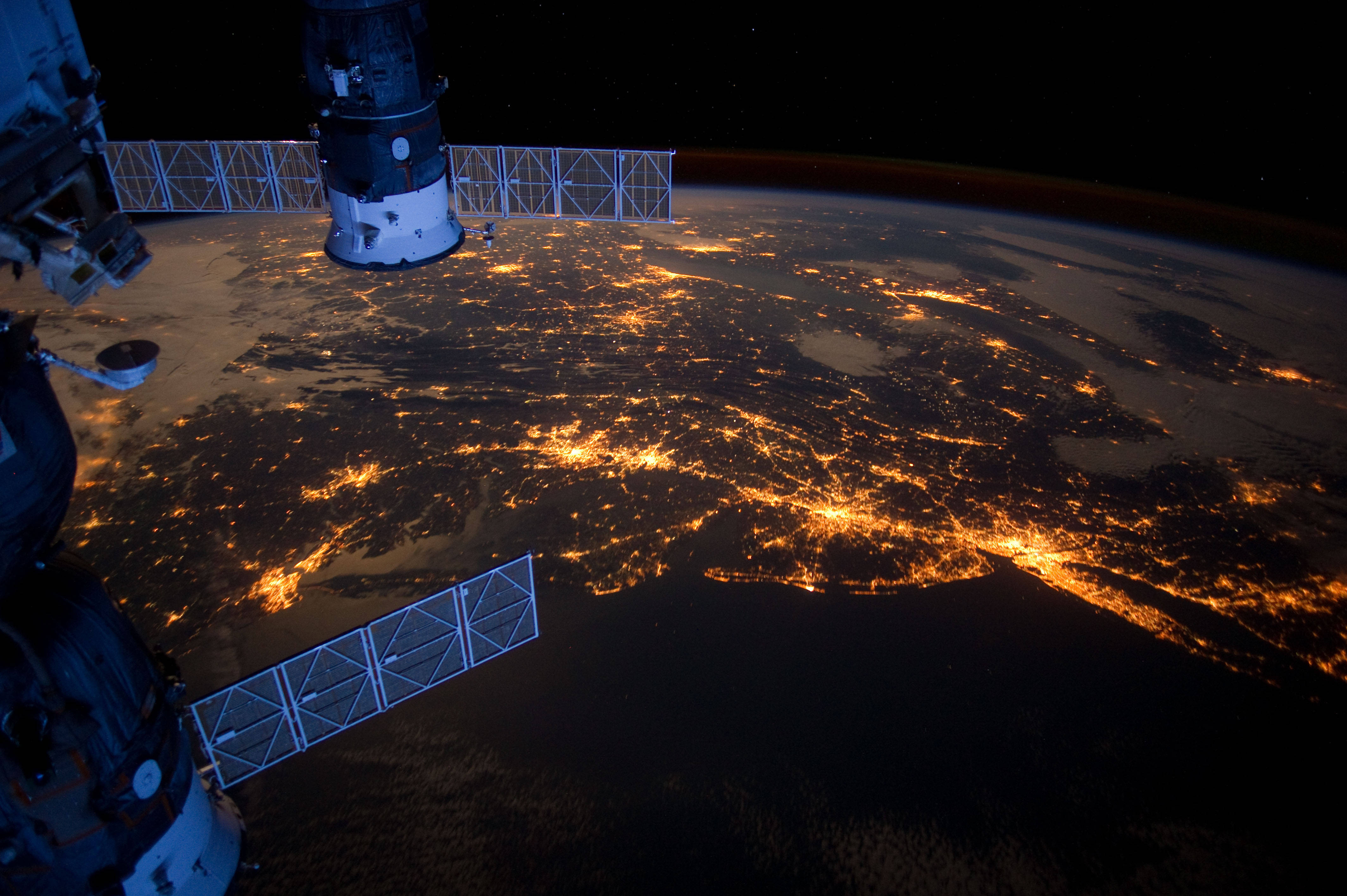 酷炫太空 桌布 壁紙 — 從國際太空站看到的壯麗夜景，顯示地球發光的城市燈光，映襯著黑暗的海洋和陸地。
