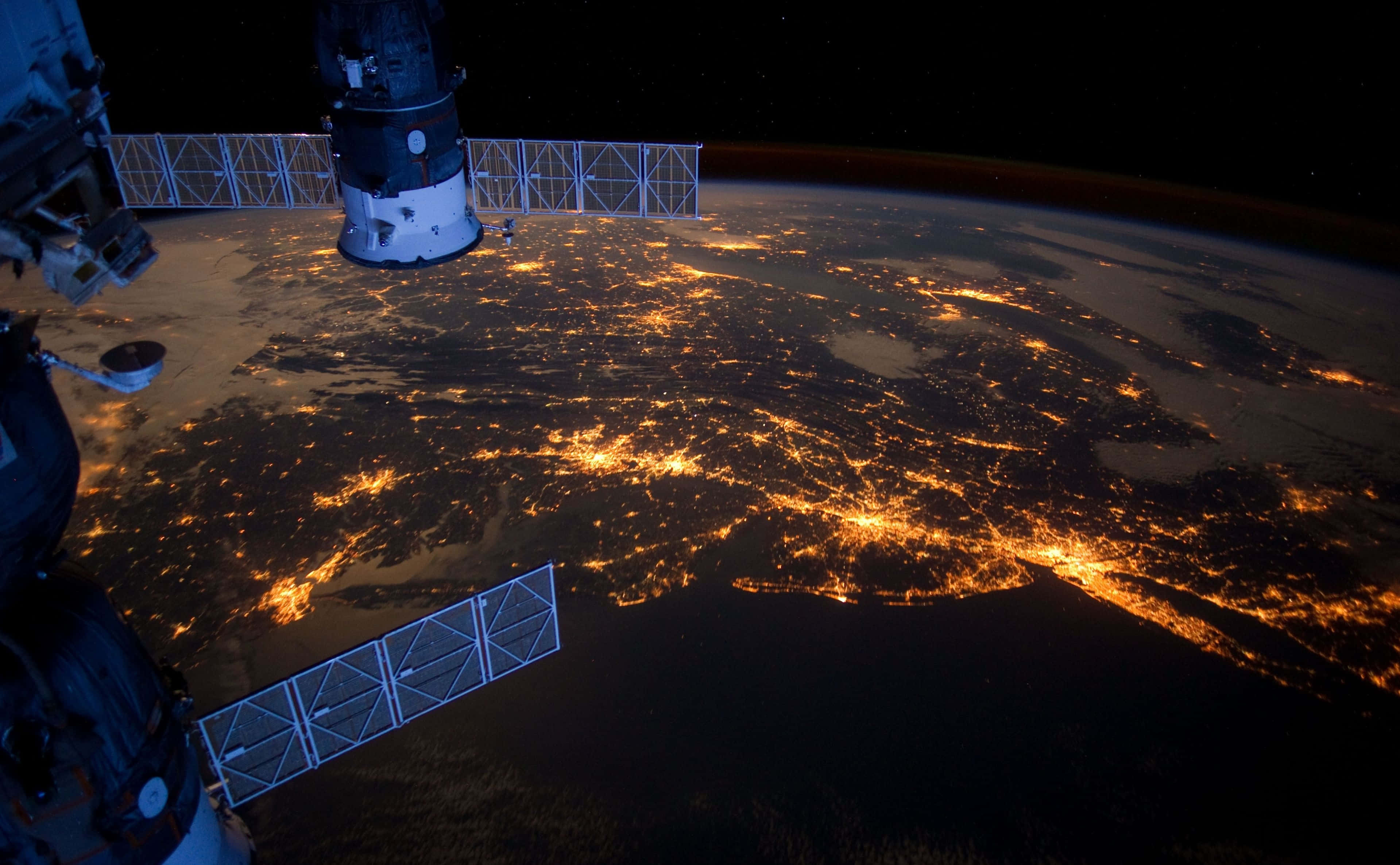 NASA 動態圖片 桌布 壁紙 — 從國際太空站看到的壯麗景色，顯示了夜間地球發光的城市燈光，映襯著黑暗的海洋和陸地。