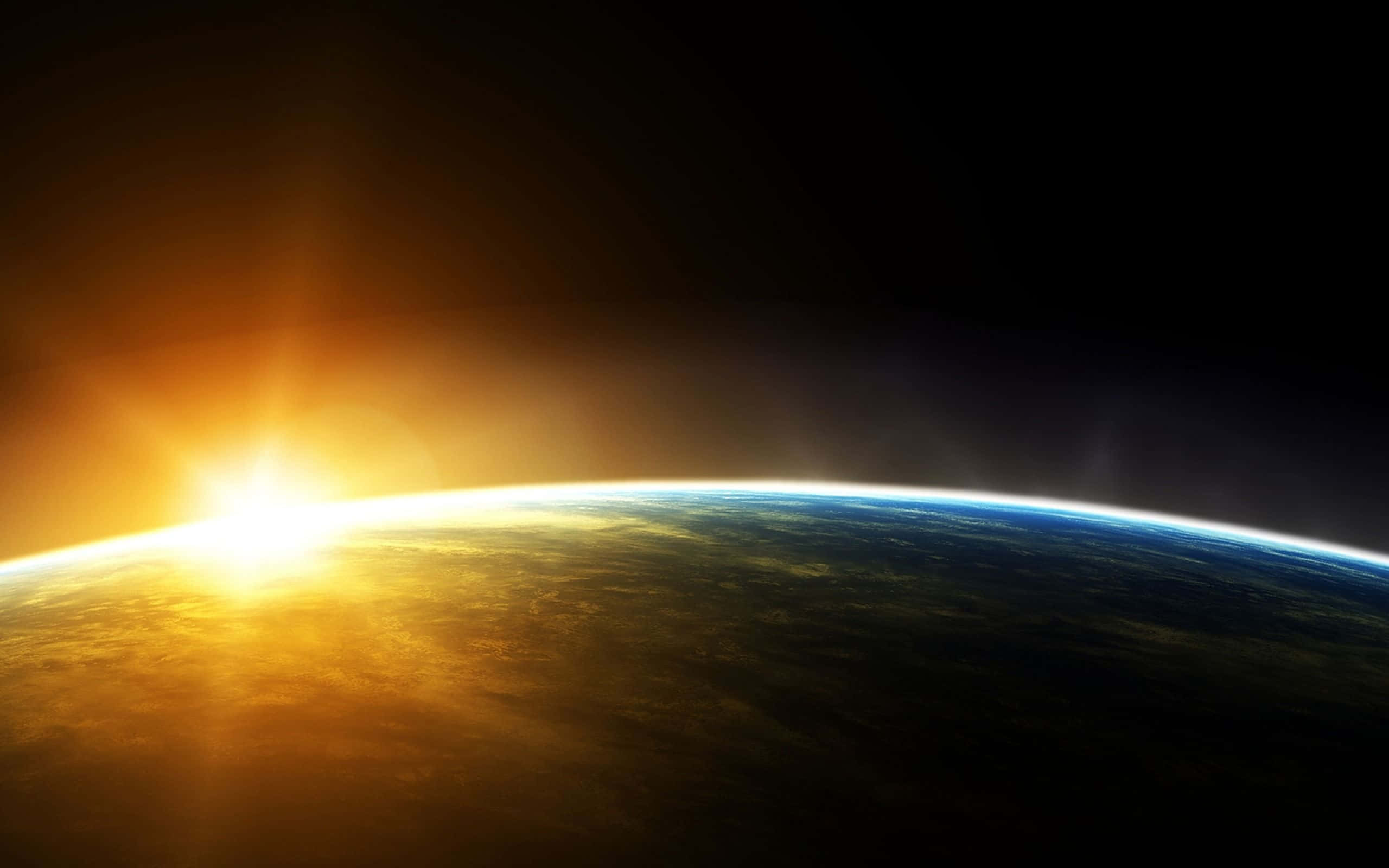Sunrise Desktop 桌布 壁紙 — 從太空俯瞰地球的壯麗景色，太陽從彎曲的地平線升起，將金色光芒灑在雲層和海洋上。