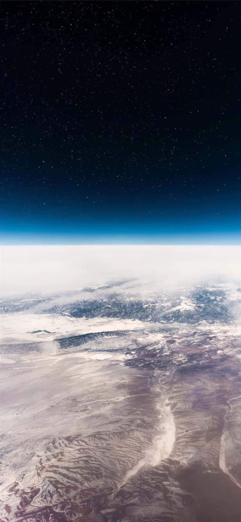 iPhone 11 桌布 壁紙 — 從太空俯瞰地球的壯麗景色，展現了白雪覆蓋的山脈地形上方的星空夜空。