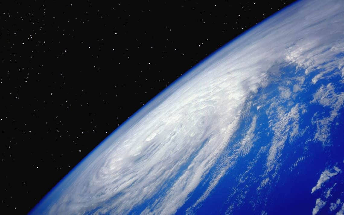 ubuntu 桌布 壁紙 — 從太空俯瞰地球的壯麗景色，展現深藍色海洋上旋轉的白雲，背景是星光閃爍的黑色虛空。
