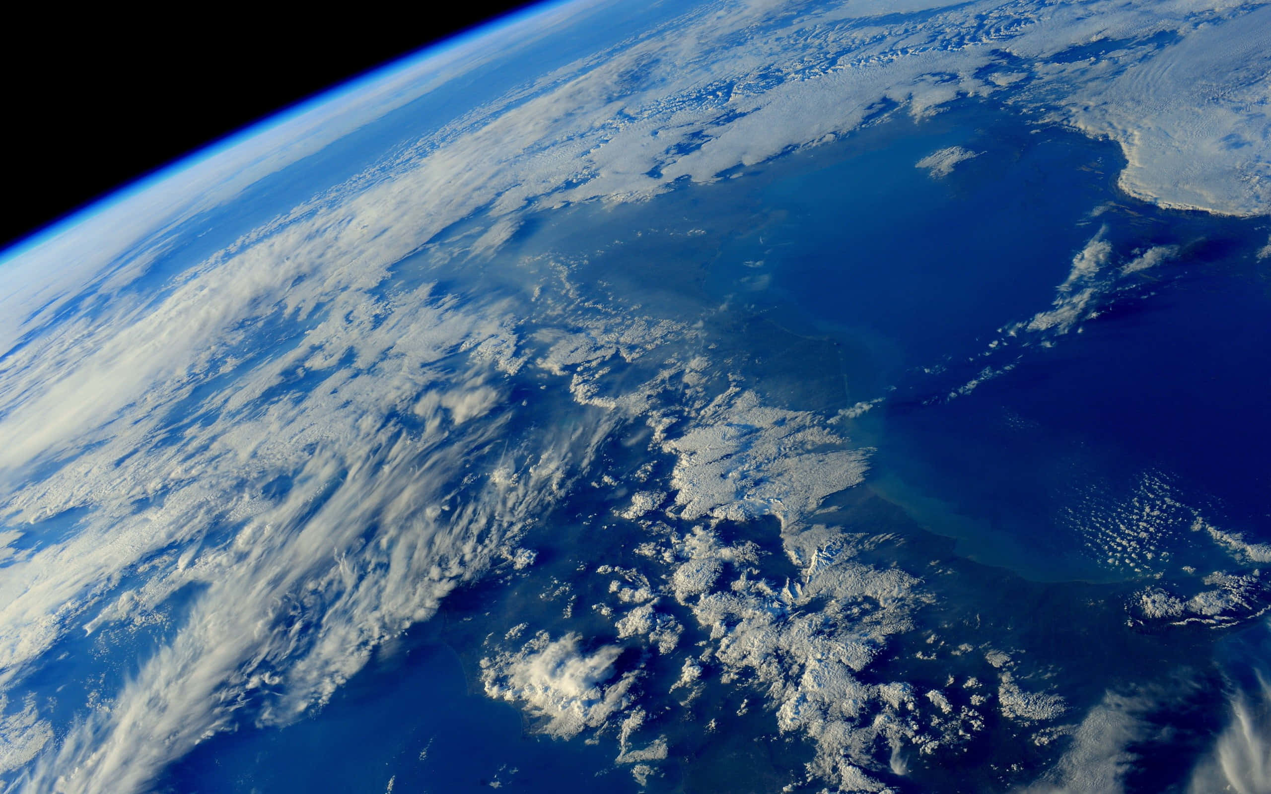太空 桌布 壁紙 — 從太空俯瞰地球的壯麗景色，展現深藍色海洋和冰封陸地上旋轉的白雲。