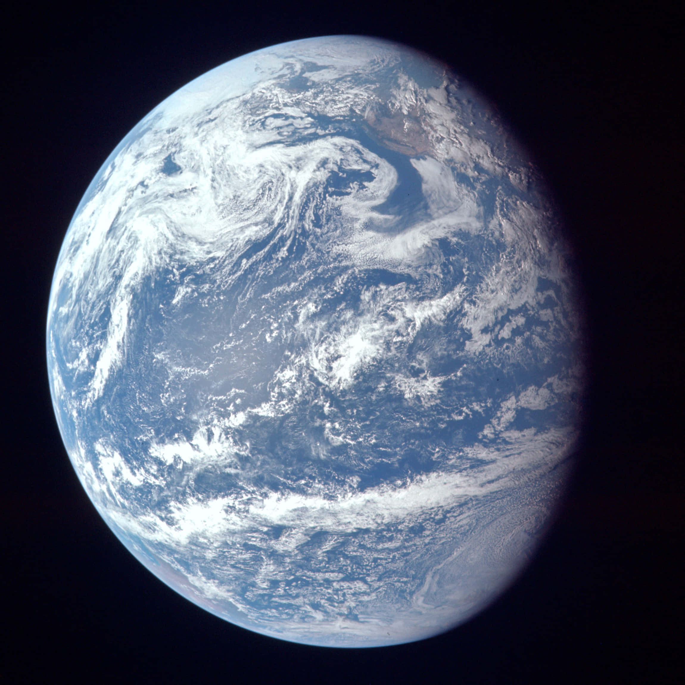 World 桌布 壁紙 — 從太空俯瞰地球的壯麗景色，展現深藍色海洋和陸地上方旋轉的白色雲層，背景是太空的黑色虛空。