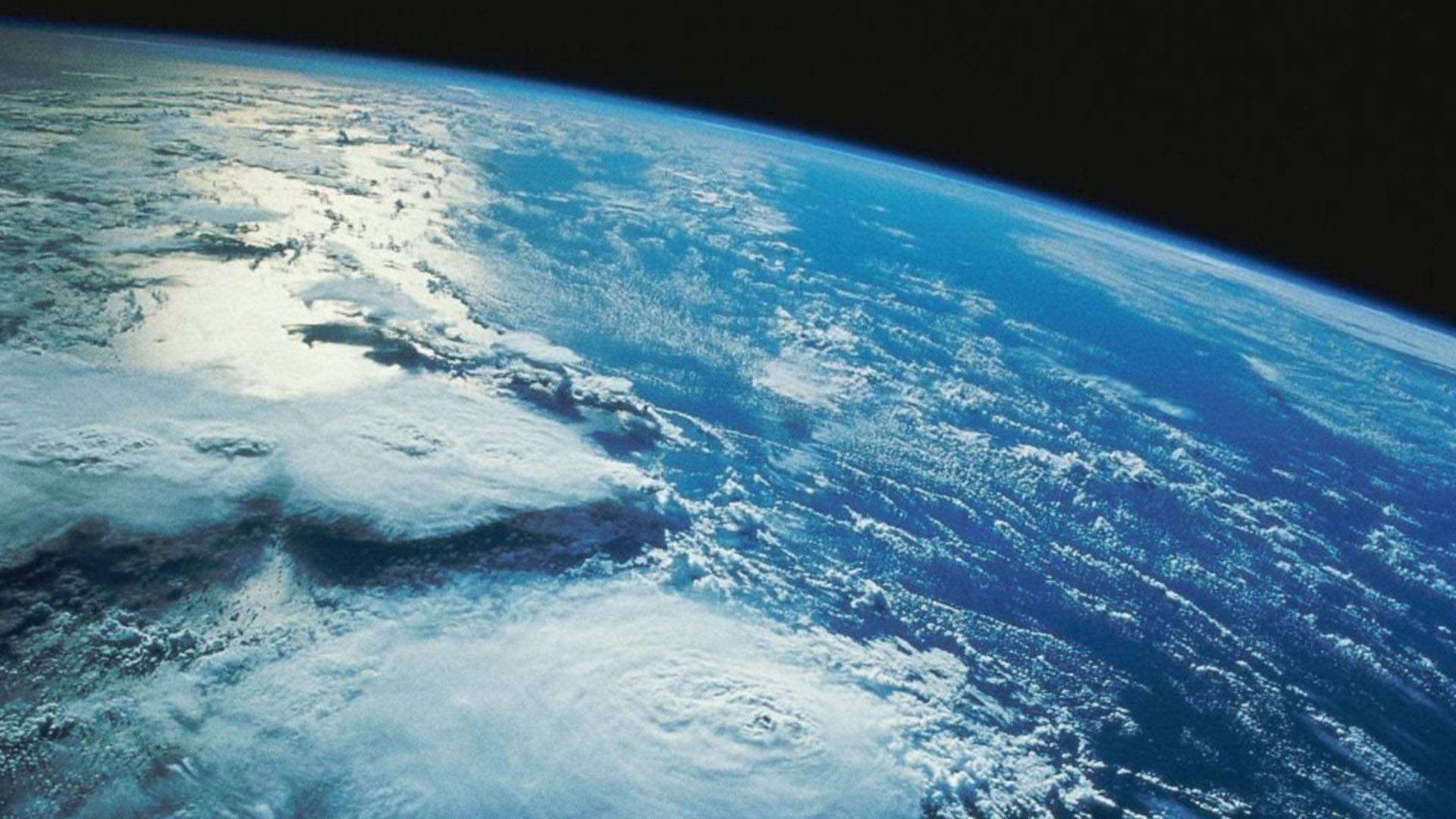 NASA 動態圖片 桌布 壁紙 — 從太空俯瞰地球的壯麗景色，展現陽光下深藍色海洋和陸地上方旋轉的白色雲層。