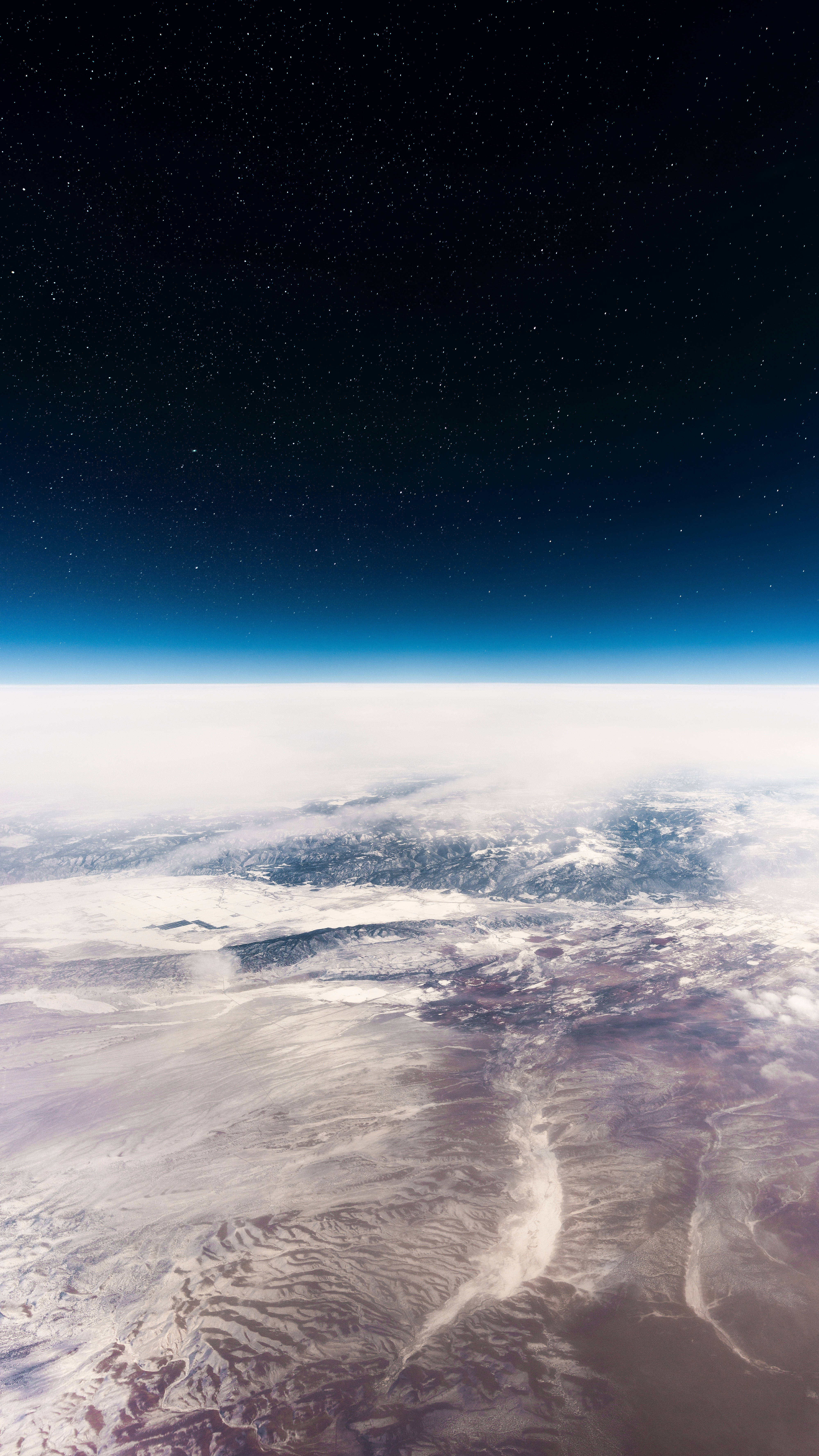 星際效應 桌布 壁紙 — 從太空俯瞰地球的壯麗景色，顯示出雪覆蓋的山地地形上方繁星點點的夜空。