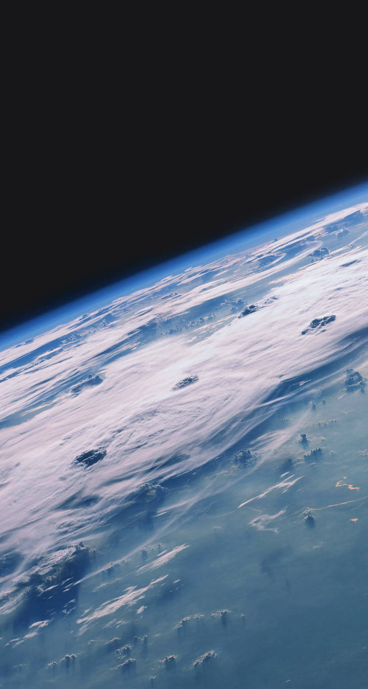 太空 iPhone 桌布 壁紙 — 從太空俯瞰地球的壯麗景色，顯示出藍色海洋和陸地上空旋轉的白色雲層，背景是太空的黑色虛空。