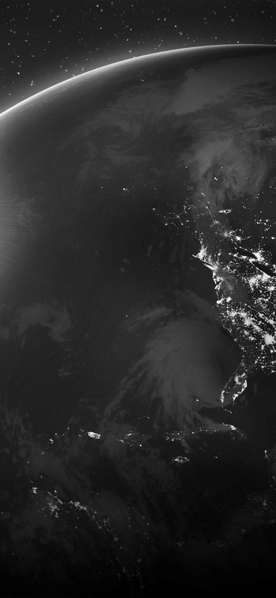 行星動畫 桌布 壁紙 — 從太空俯瞰地球的黑白壯麗景象，城市燈光在黑暗的海洋和旋轉的雲層中閃爍。