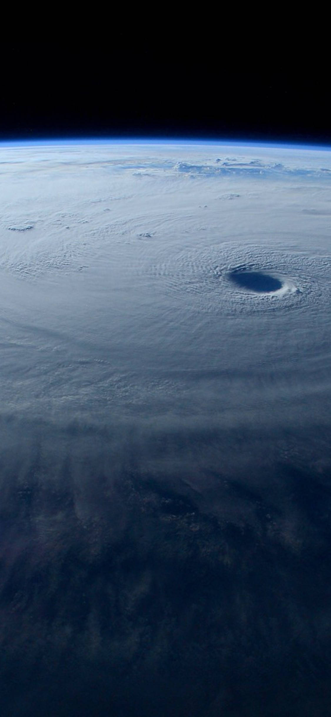 Hurricane 桌布 壁紙 — 從太空看，一個巨大的颶風在地球彎曲的地平線上旋轉，帶有黑暗的風眼和旋轉的雲層。