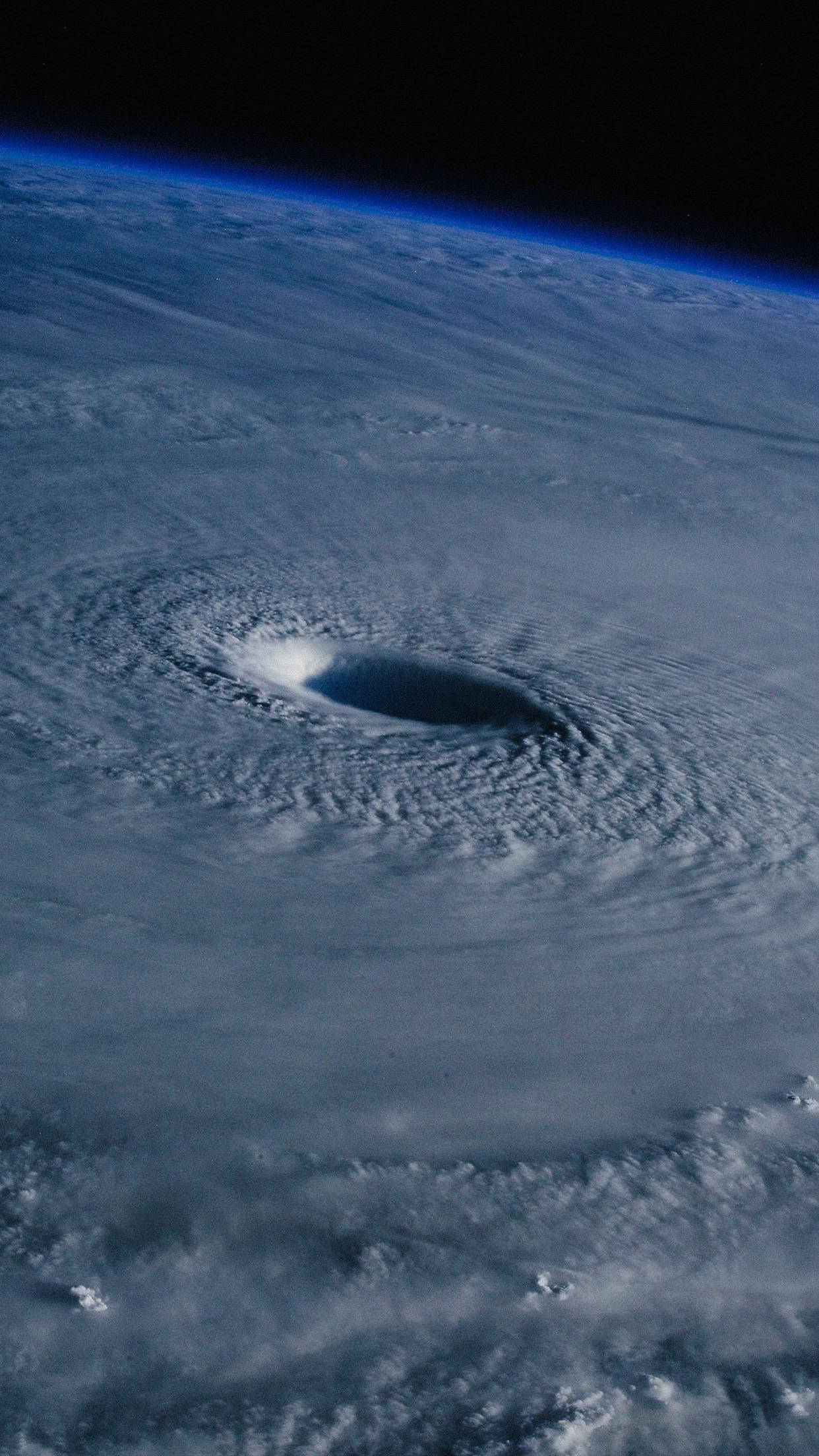 Hurricane 桌布 壁紙 — 從太空看，一個巨大的颶風在地球的藍色曲線上旋轉，中心有一個黑暗的風眼。