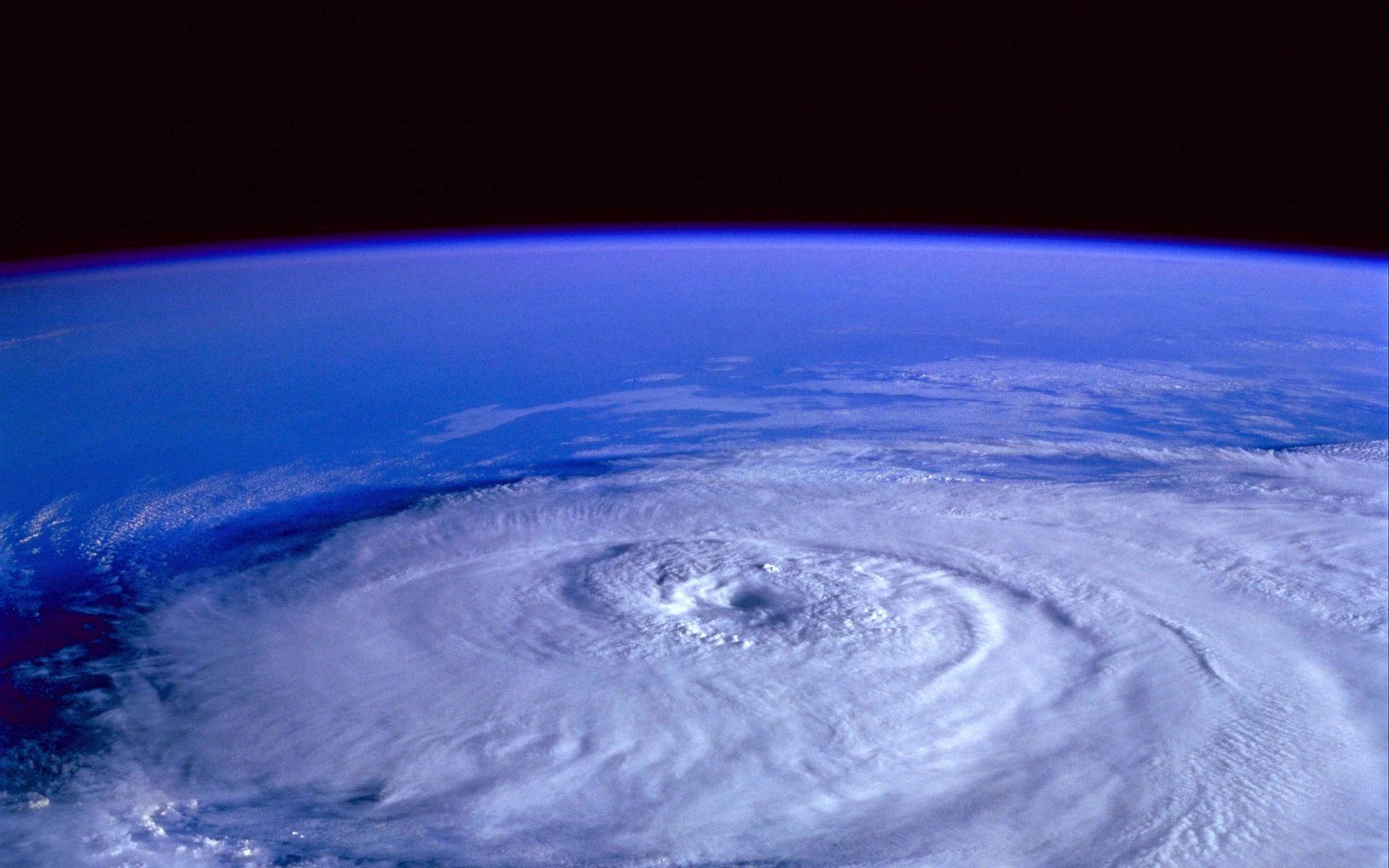 Hurricane 桌布 壁紙 — 從太空看到一個巨大颶風在地球的藍色曲線上旋轉，上方是黑暗的虛空。