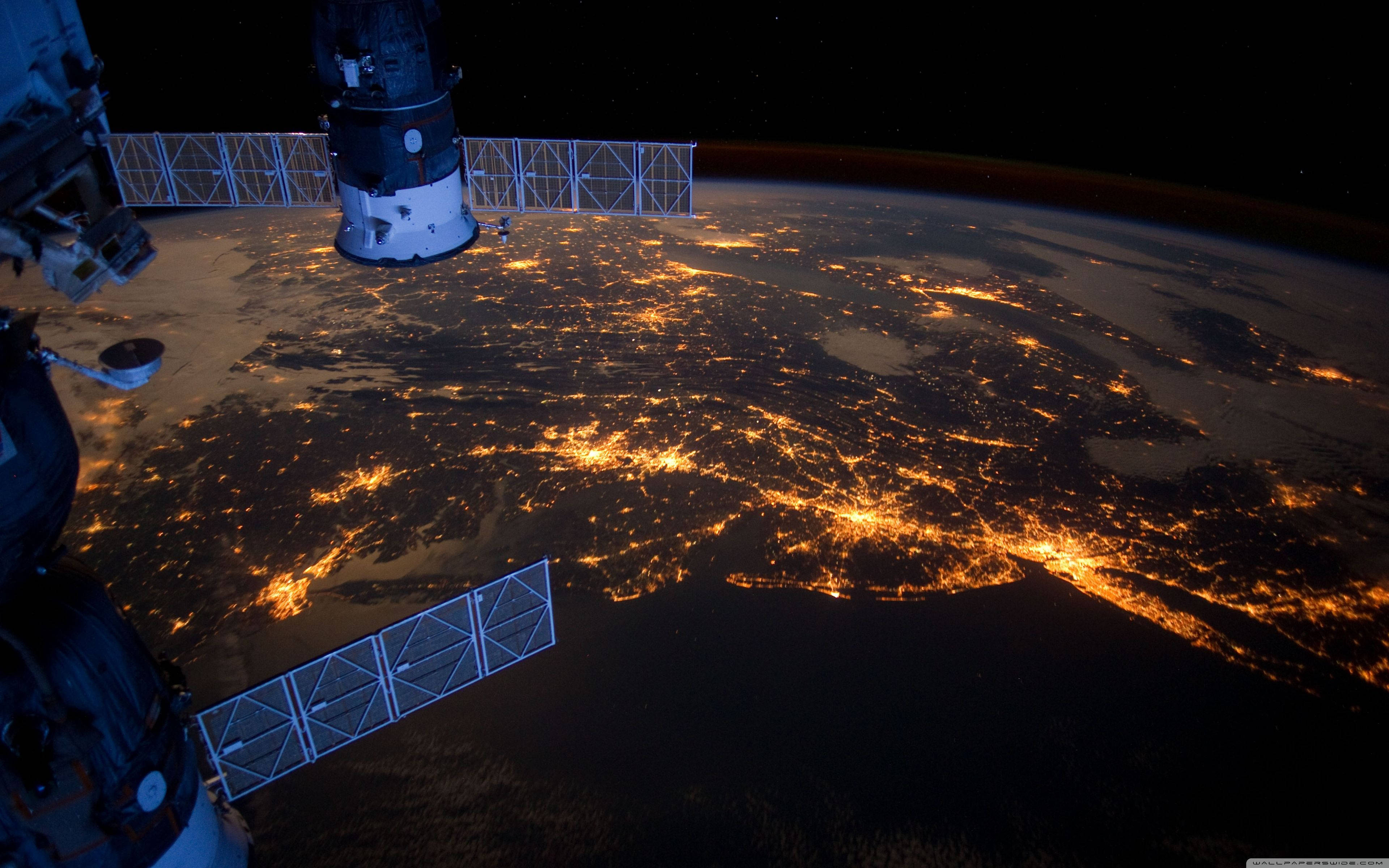 NASA 動態圖片 桌布 壁紙 — 從太空看到的壯麗景色顯示了地球彎曲的地平線，在黑色虛空中閃爍著金色的城市燈光。