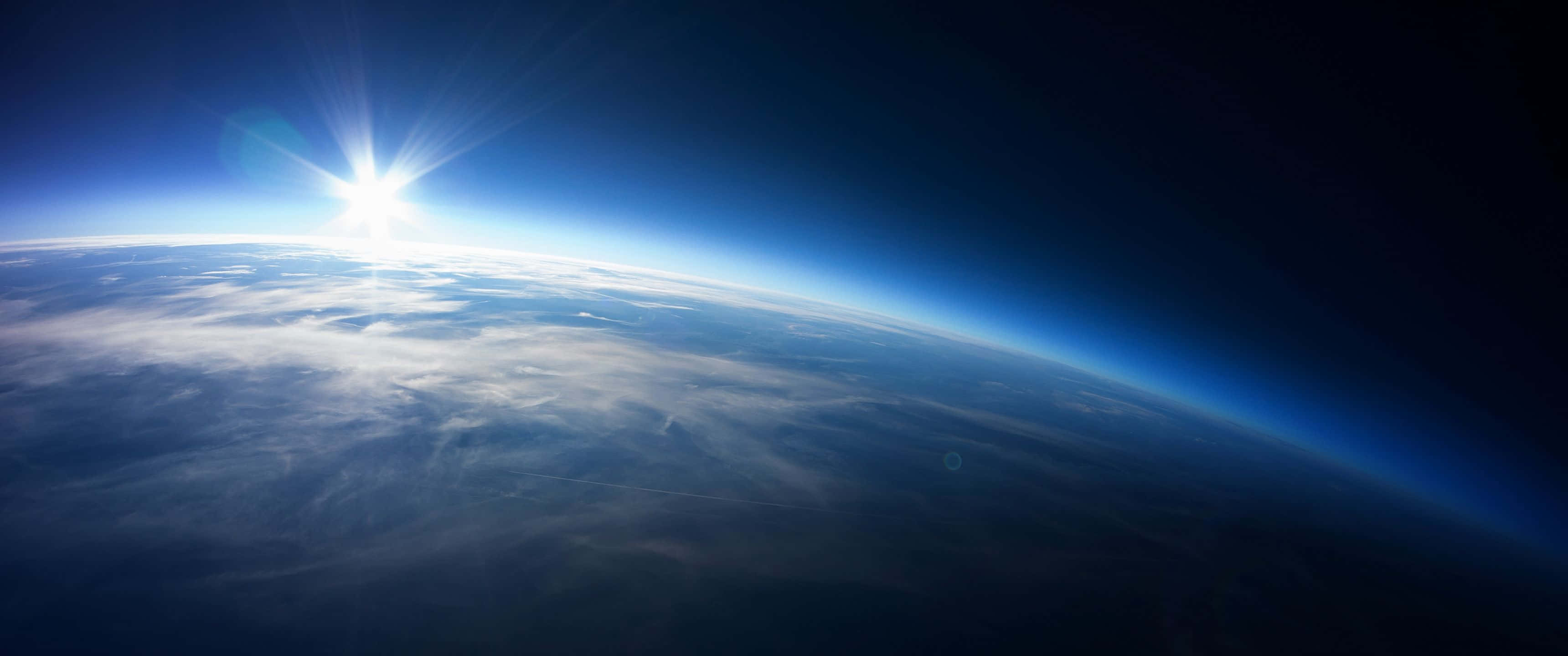 外太空 桌布 壁紙 — 從太空看地球上的日出，發光的地平線和下方的雲層。