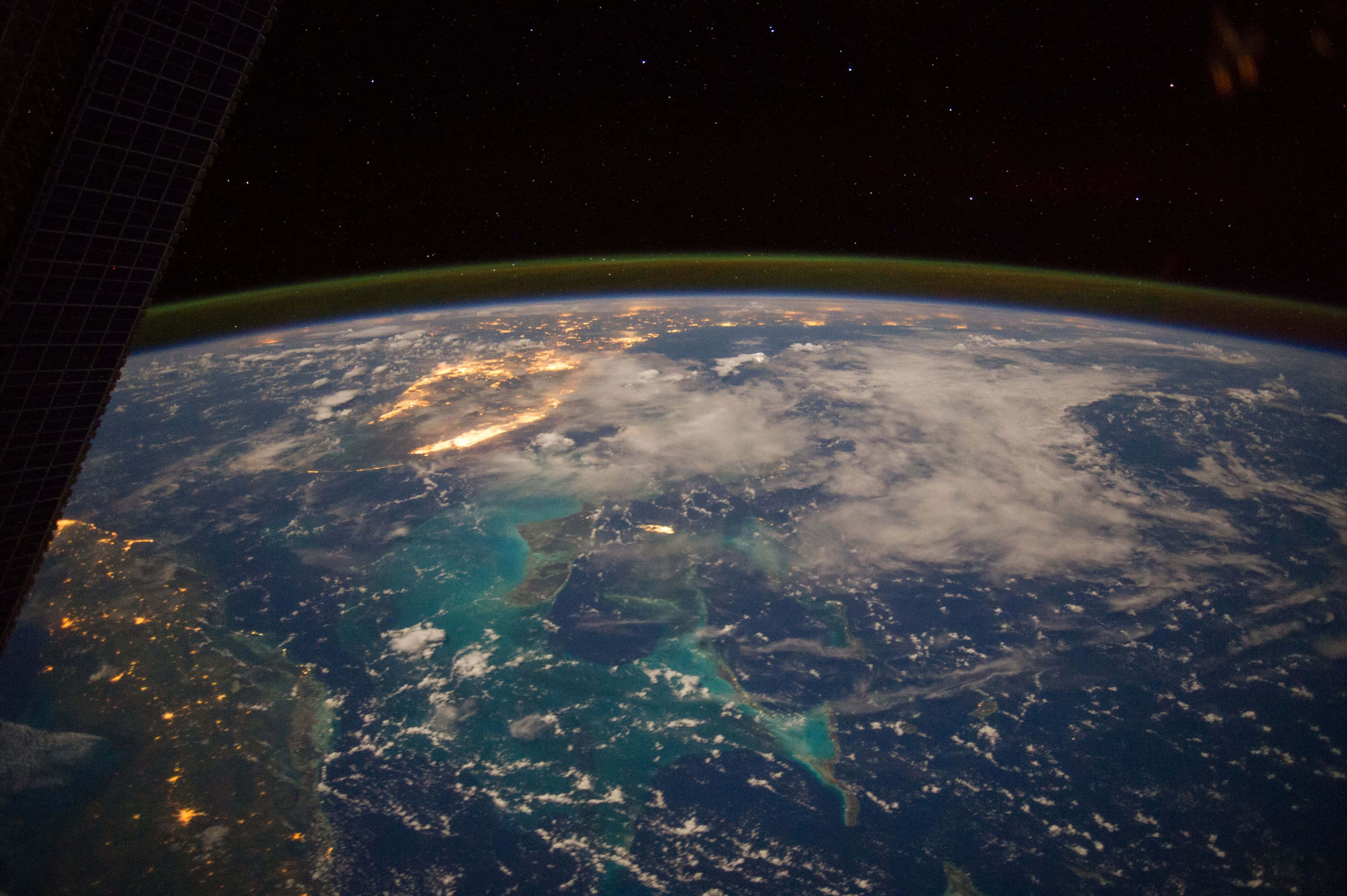 Flat Earth 桌布 壁紙 — 從太空觀看地球，下方有發光的城市燈光和碧綠海水，背景是繁星點點的黑色天空。
