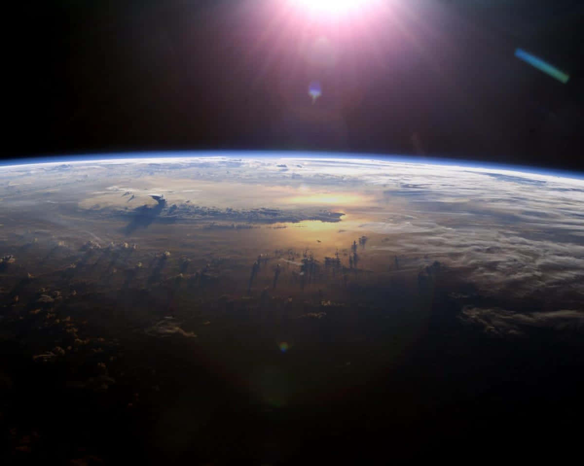 Global Warming 桌布 壁紙 — 從太空觀看地球，太陽耀斑照亮雲層和曲線，背景是黑色虛空。