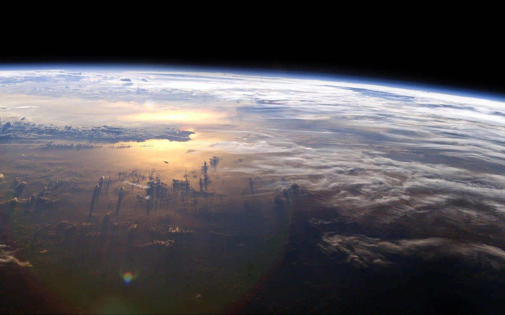 Atmosphere 桌布 壁紙 — 從太空觀看地球，金色陽光在雲層和海洋上反射，背景是黑色虛空。