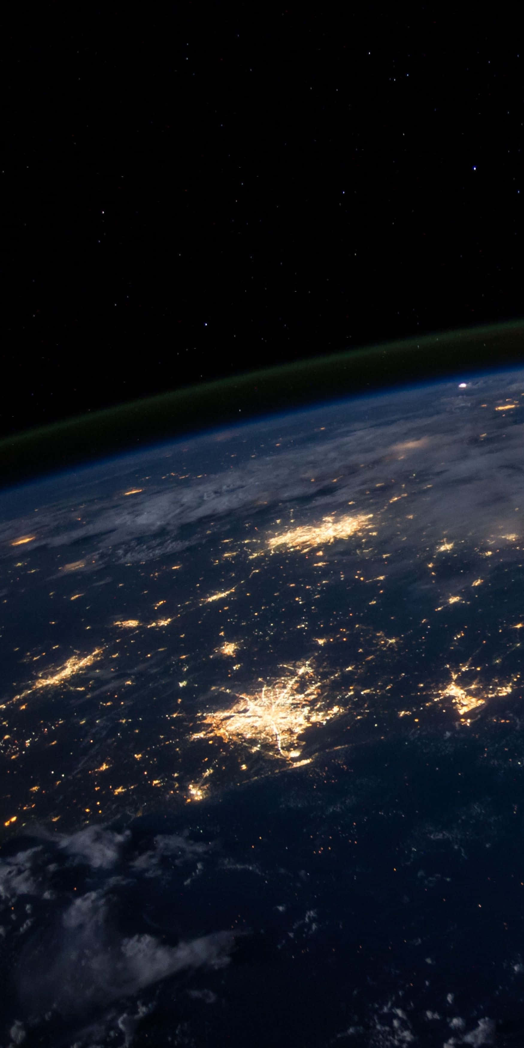 OLED 桌布 壁紙 — 從太空觀看夜晚的地球，城市燈光在黑暗的海洋和星空下閃耀。